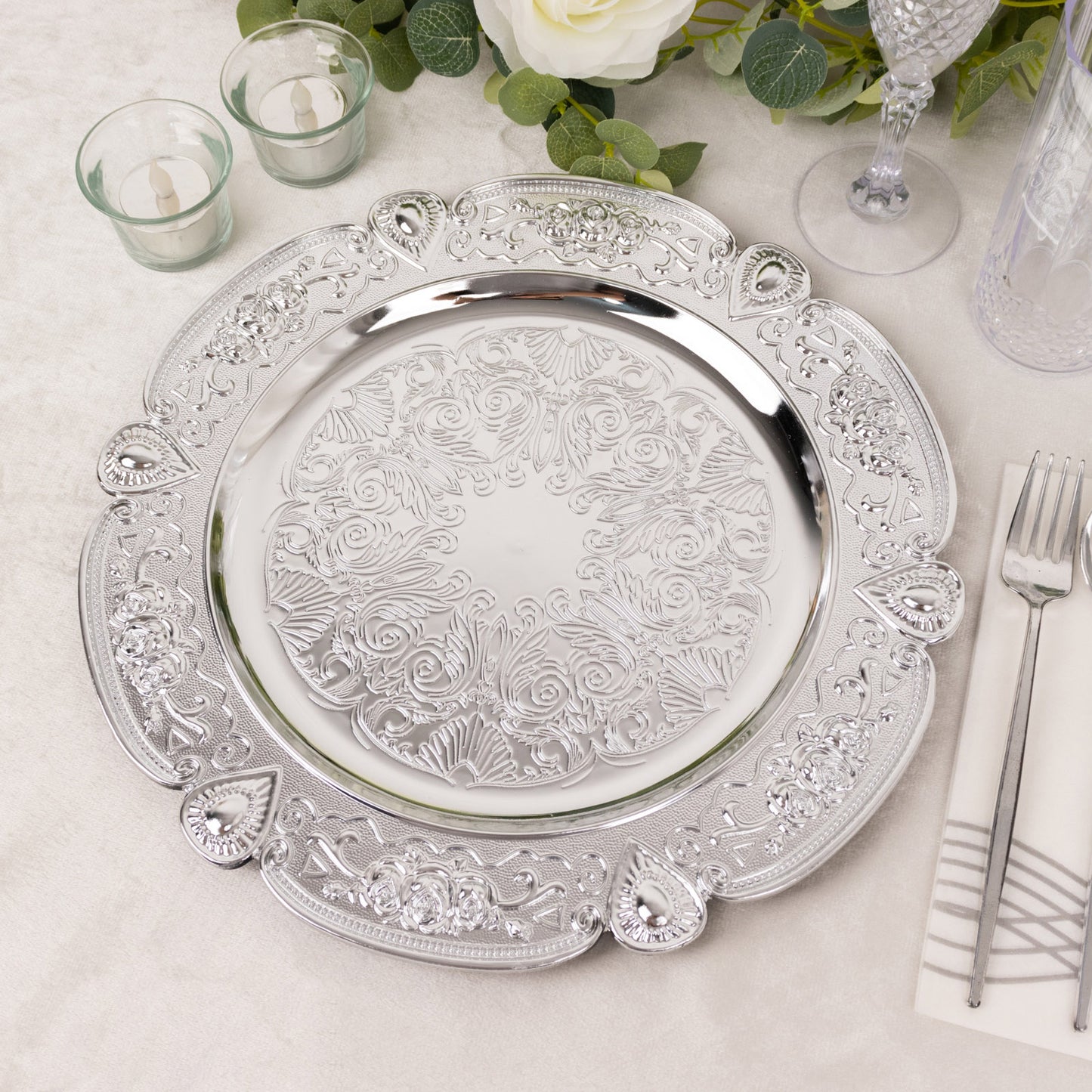 Silver round acrylic charger plate with floral embossed scalloped rim.