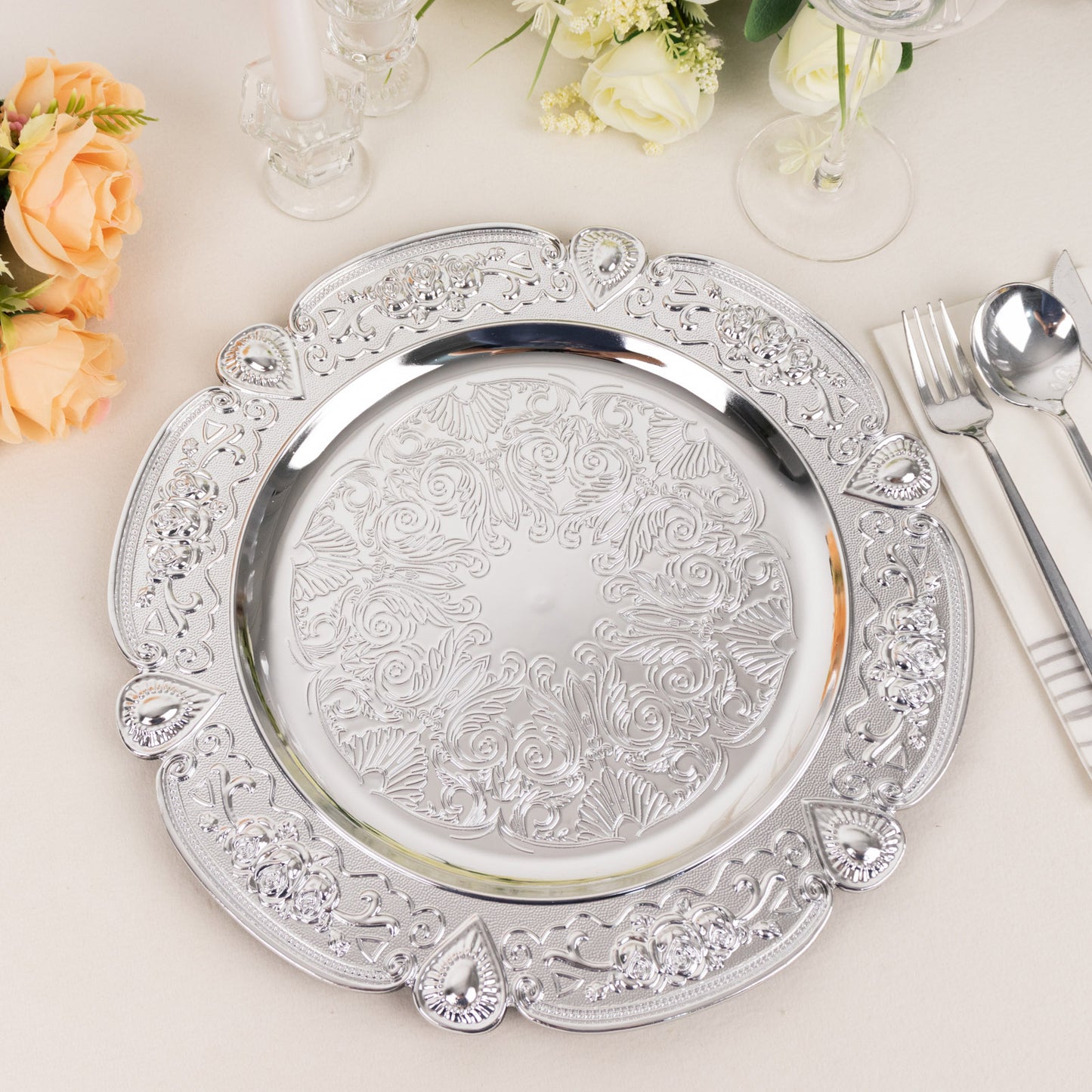 Silver round acrylic charger plate with floral embossed scalloped rim.