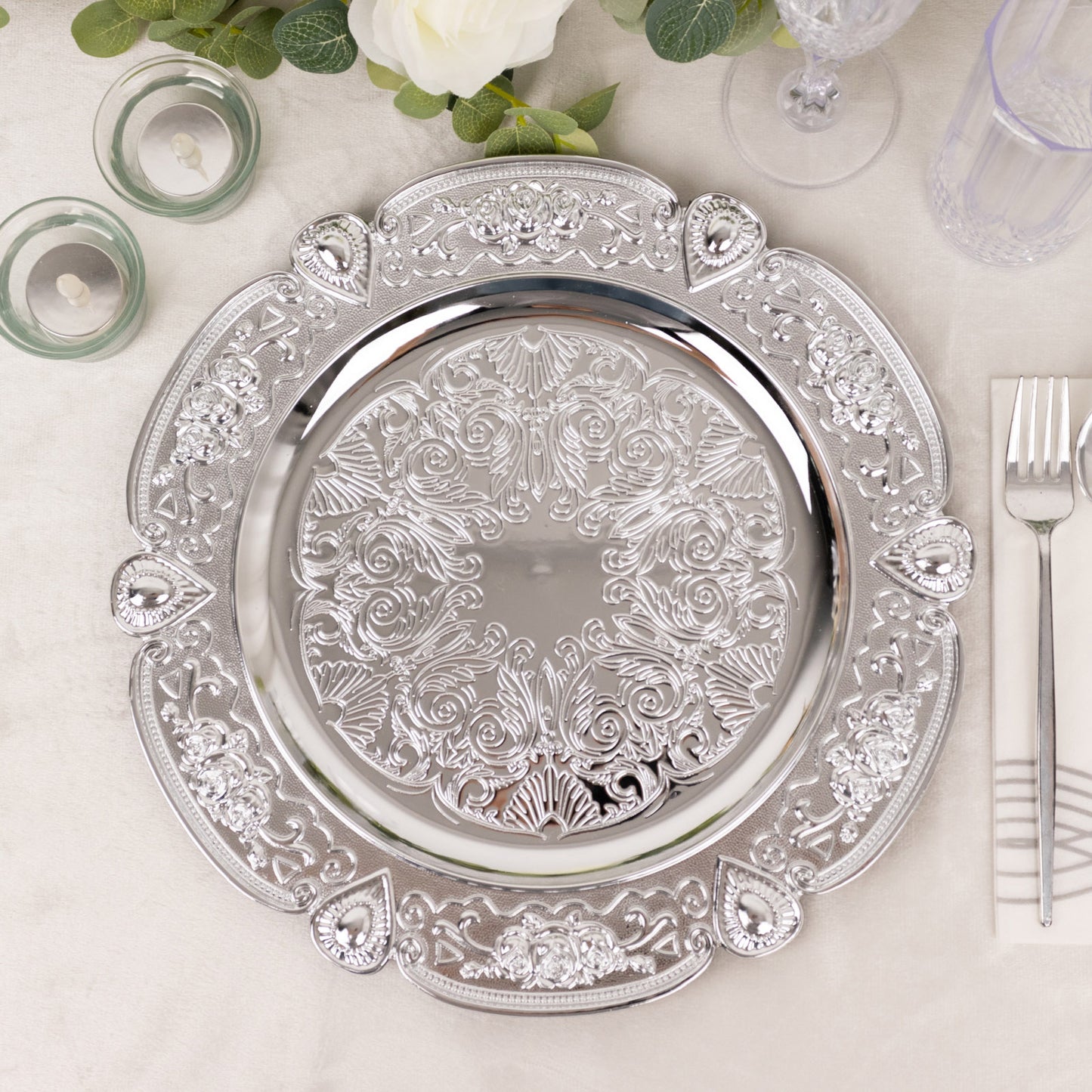Silver round acrylic charger plate with floral embossed scalloped rim.