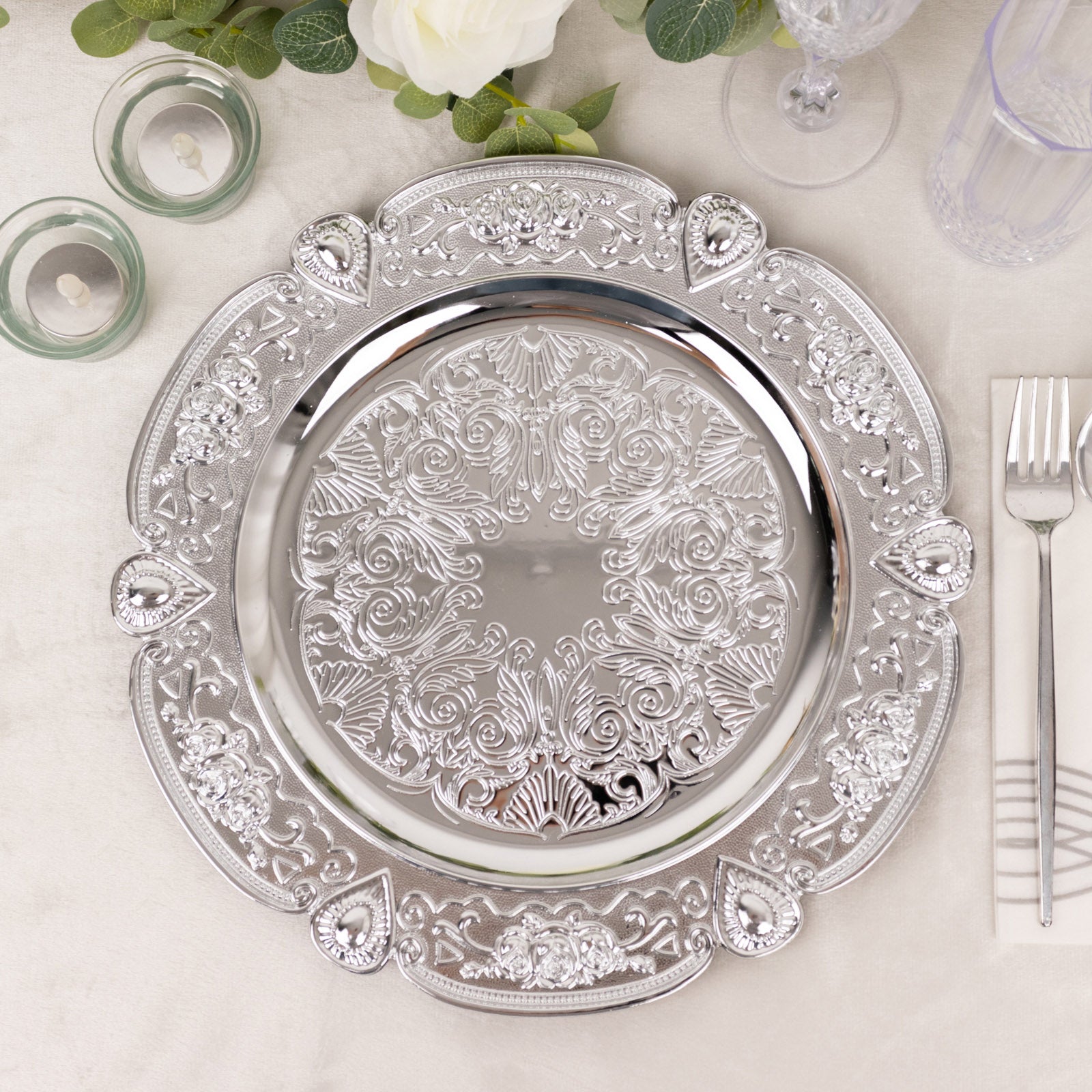 Silver round acrylic charger plate with floral embossed scalloped rim.