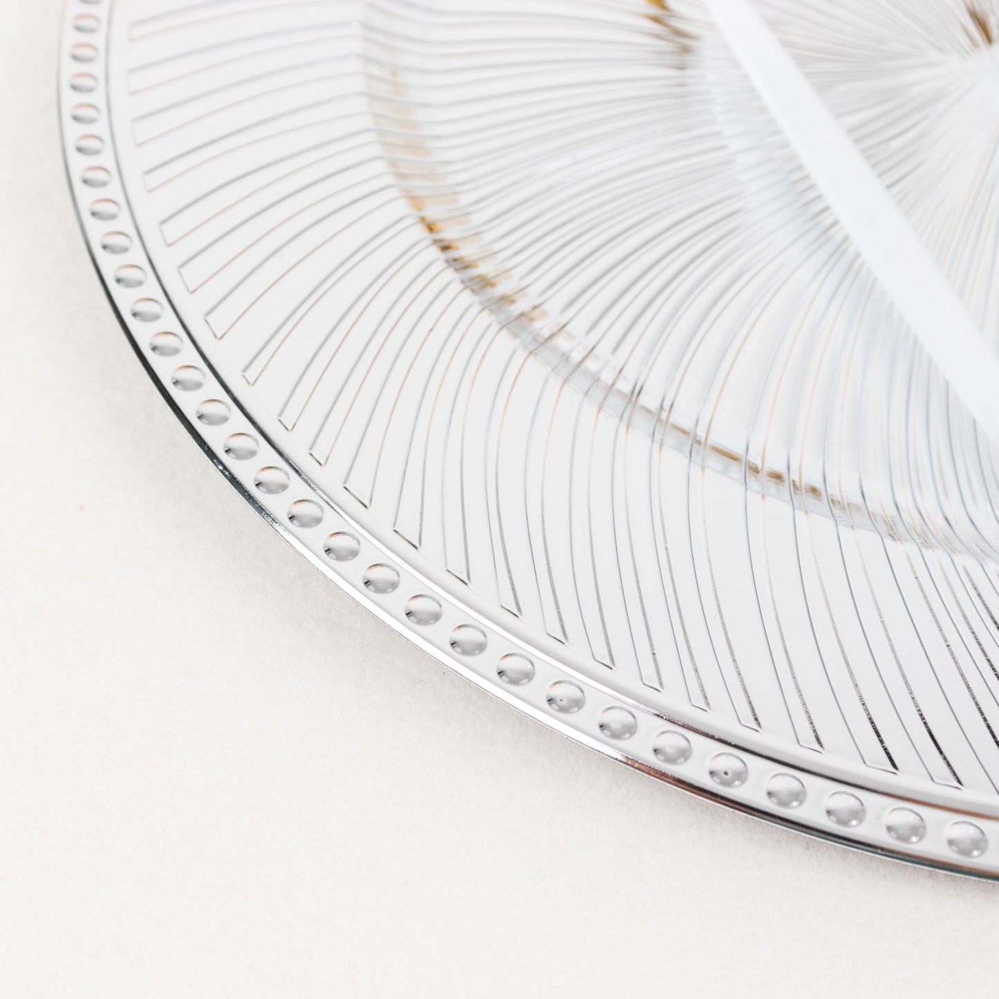 Metallic silver swirl pattern acrylic charger plate with beaded rim.