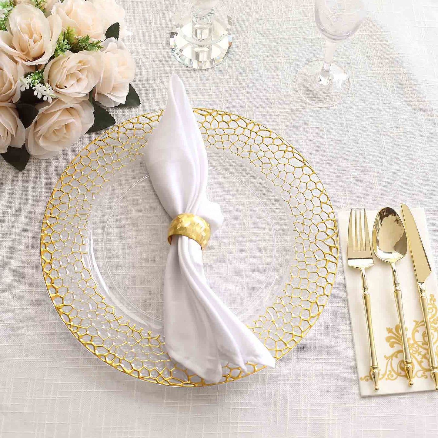 Clear acrylic charger plate with gold hammered rim on a table setting.