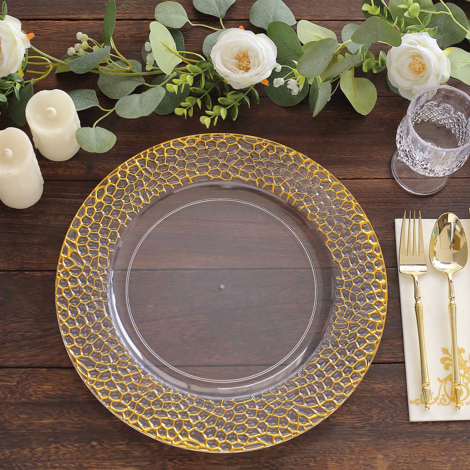 Clear acrylic round charger plate with gold hammered rim on a wooden table.