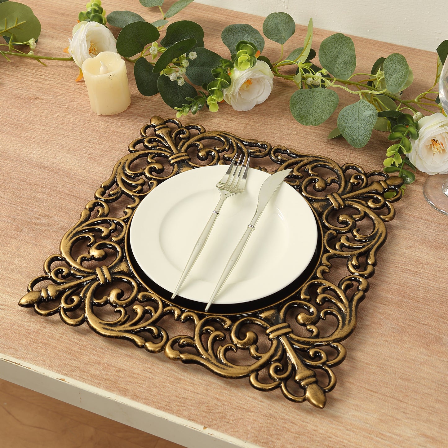Black square acrylic charger plate with antique gold lace border on a table setting.