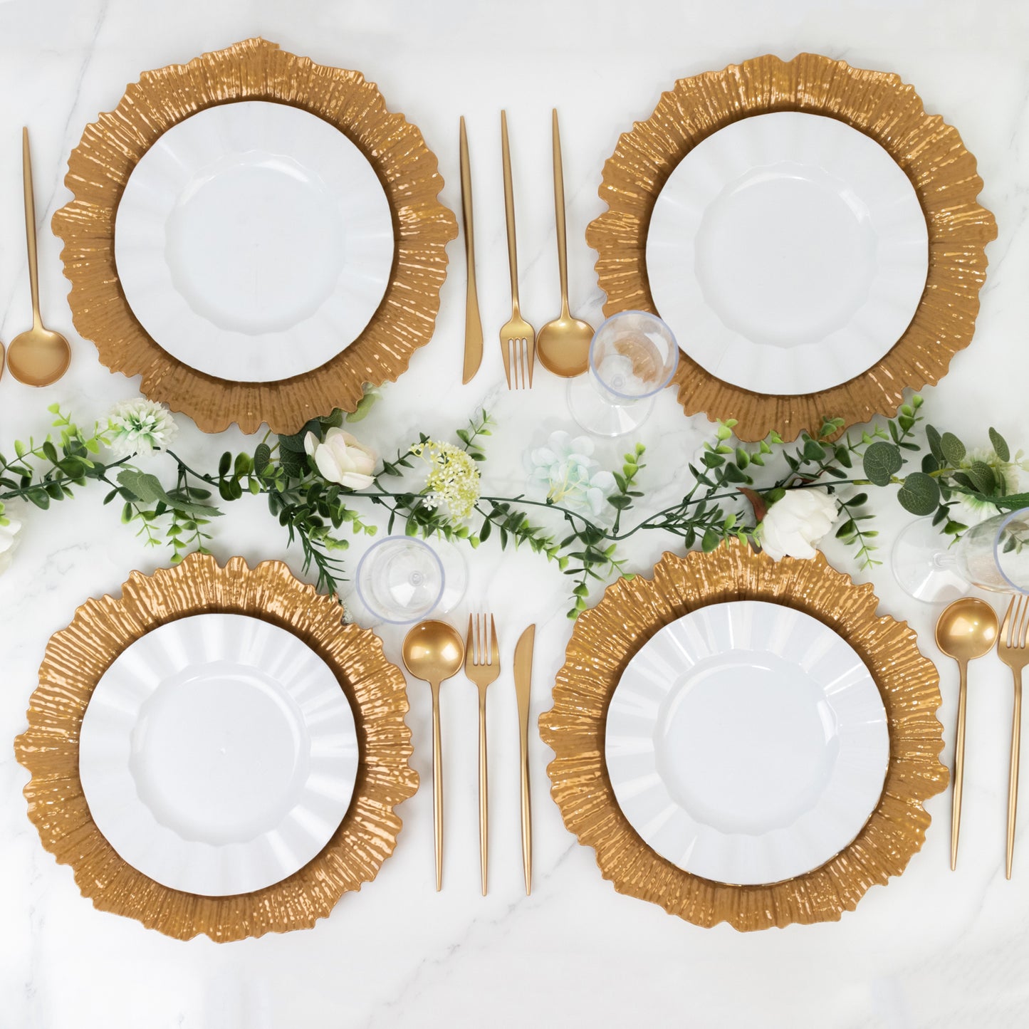 Gold charger plates arranged on a table with white dinner plates and gold cutlery.