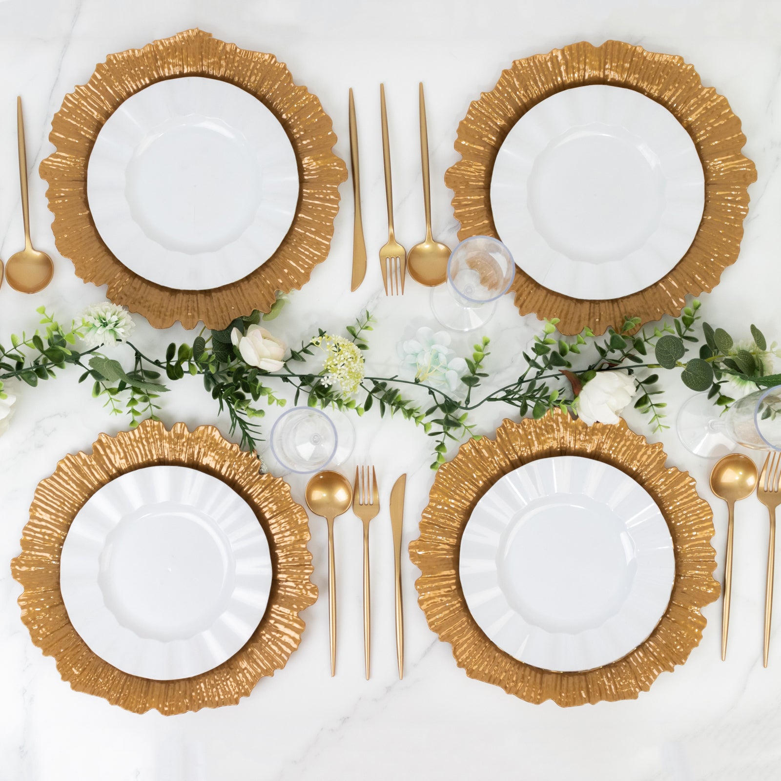 Gold charger plates arranged on a table with white dinner plates and gold cutlery.