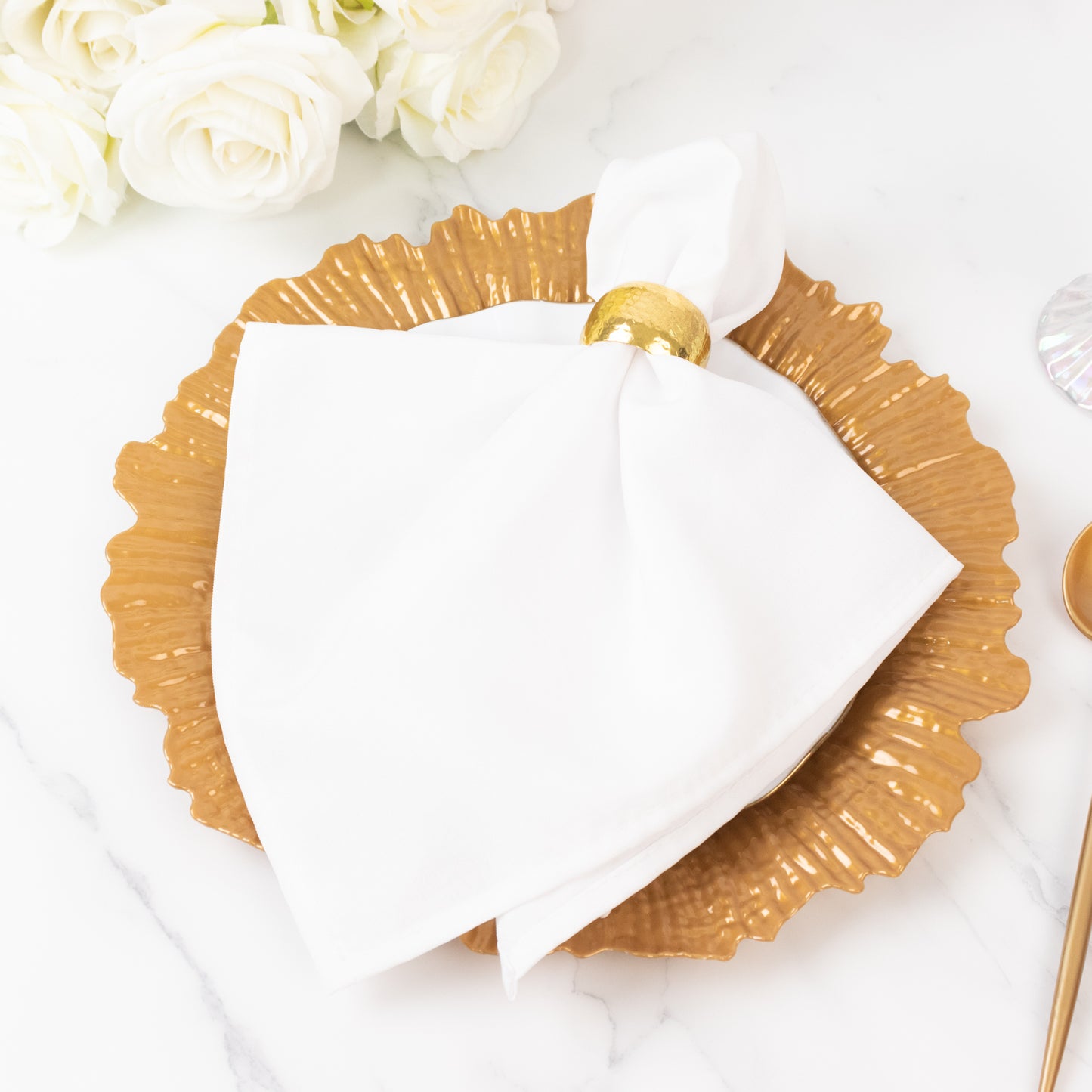 Gold charger plate with white napkin for elegant dining settings.