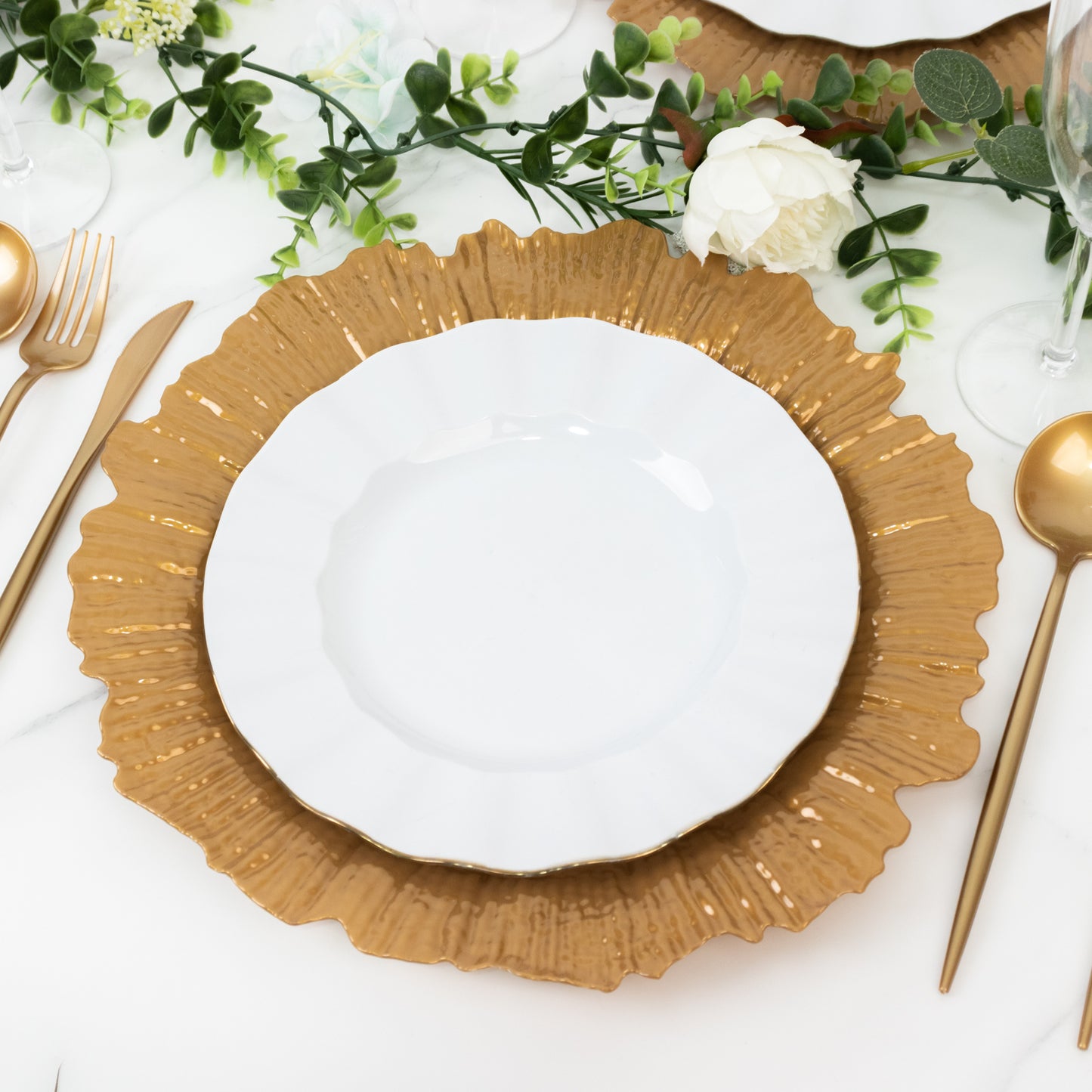 Gold charger plate with a white dinner plate on a decorative table setting.