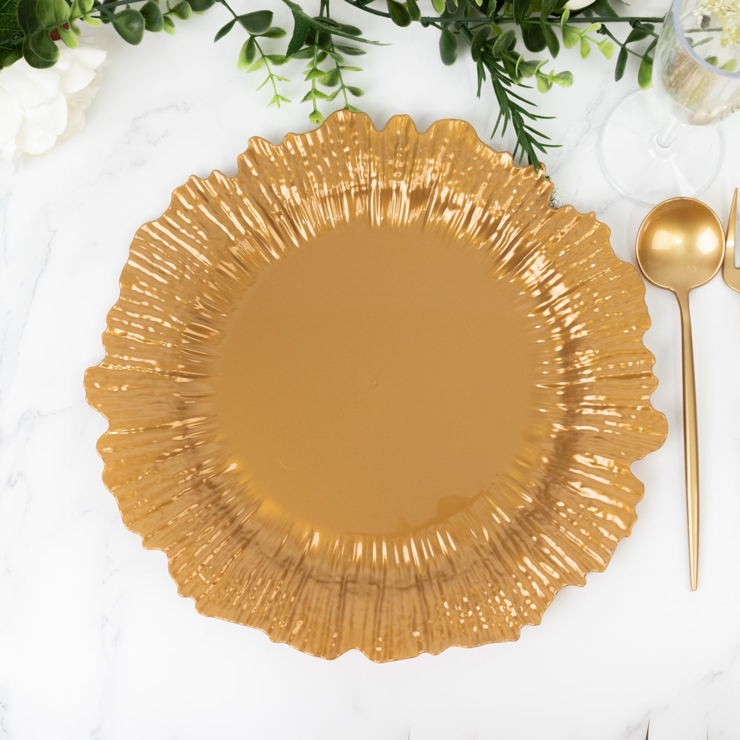 Gold charger plate with ruffled edges on a marble surface.