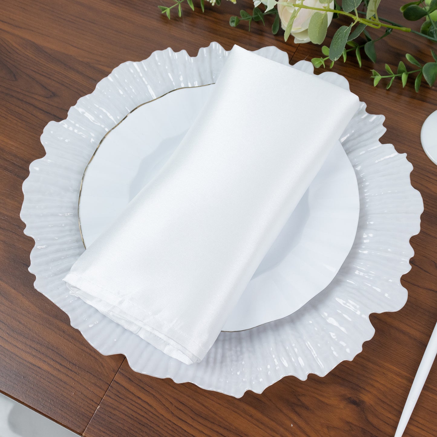 Pearl white charger plate with napkin on a wooden table.
