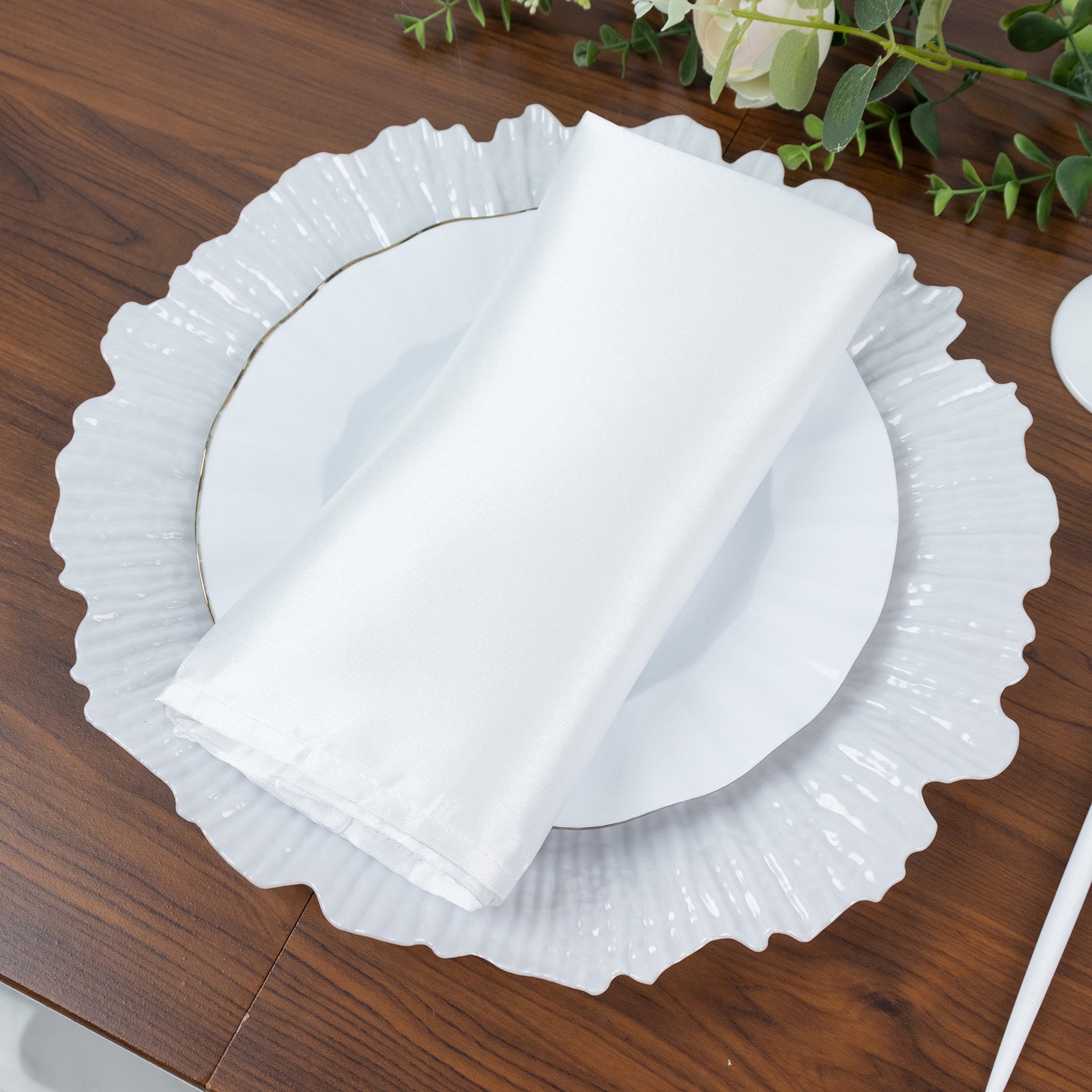 Pearl white charger plate with napkin on a wooden table.