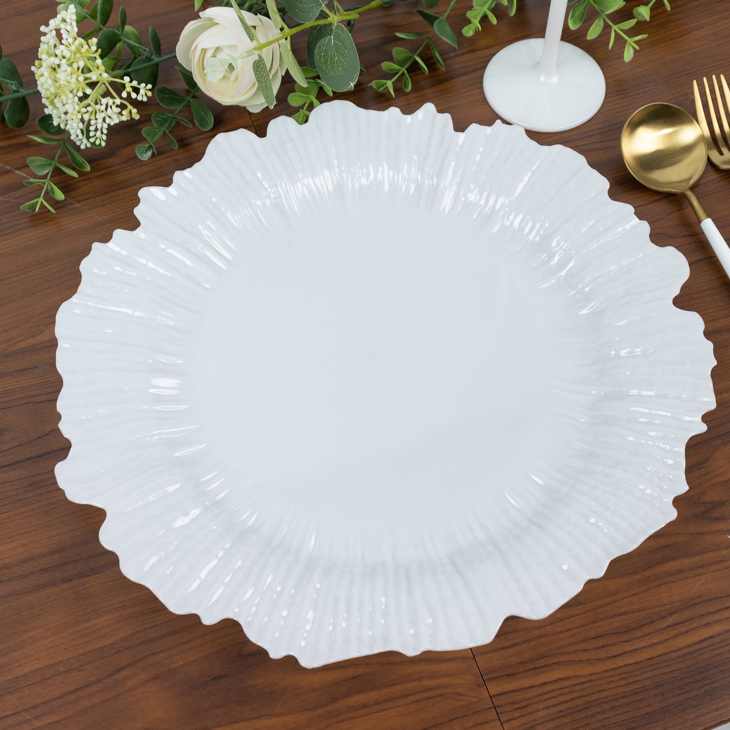 Pearl white charger plate on a wooden table with decorative elements.