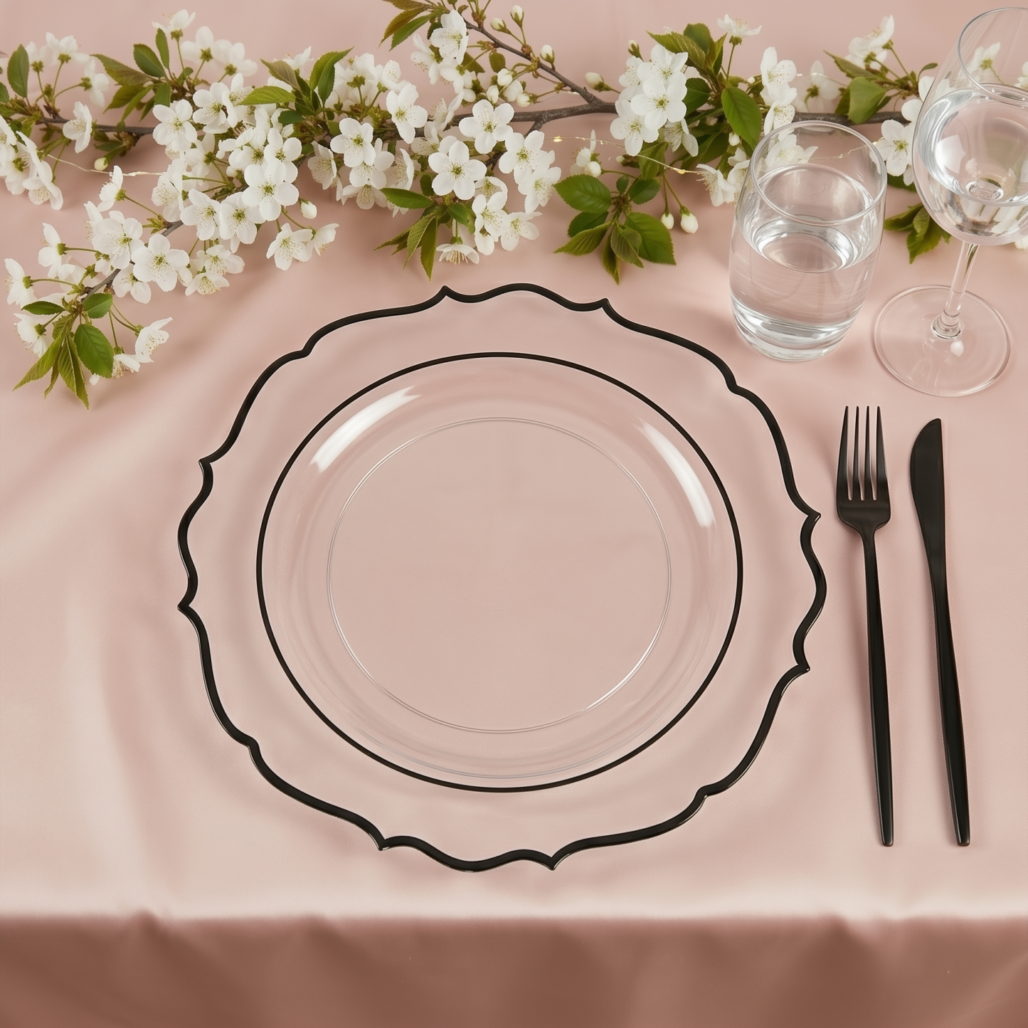 Clear charger plate with black scalloped rim on a pink tablecloth.