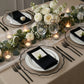 Clear charger plates with black scalloped rim on an elegant dinner table setting.