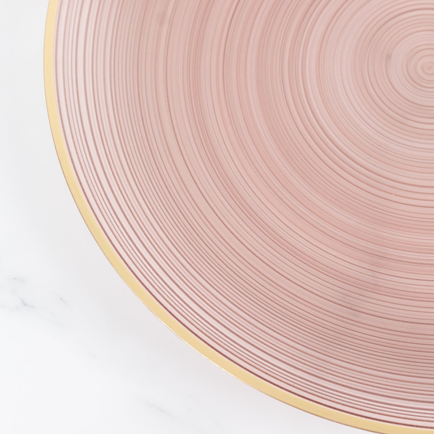 Transparent dusty rose swirl charger plate with gold rim.