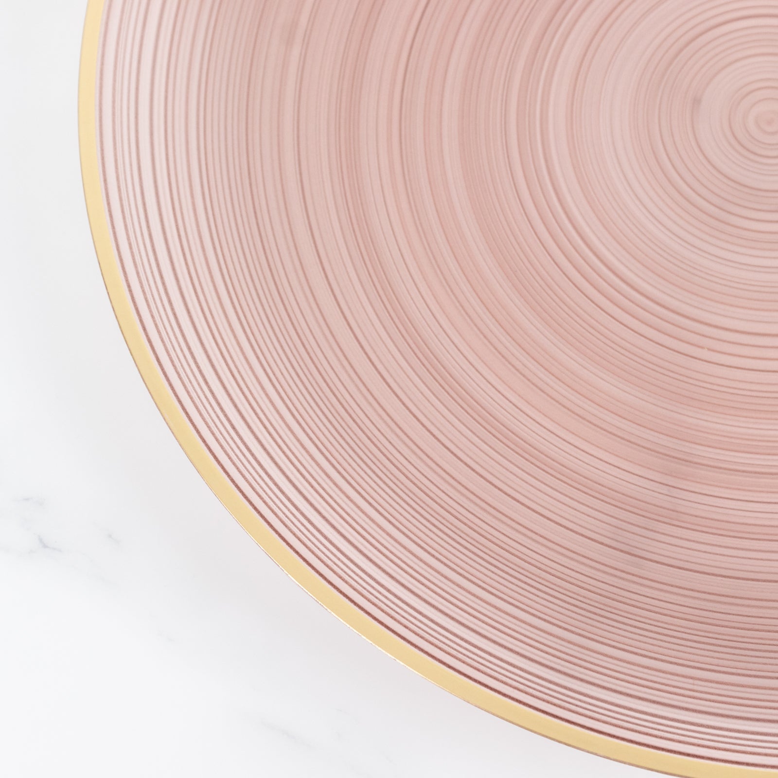 Transparent dusty rose swirl charger plate with gold rim.