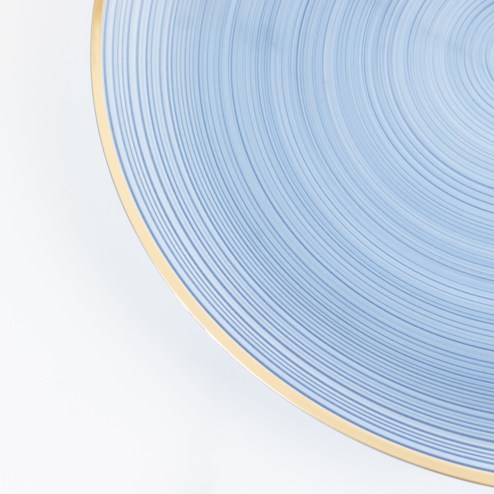 Transparent dusty blue swirl charger plate with gold rim.