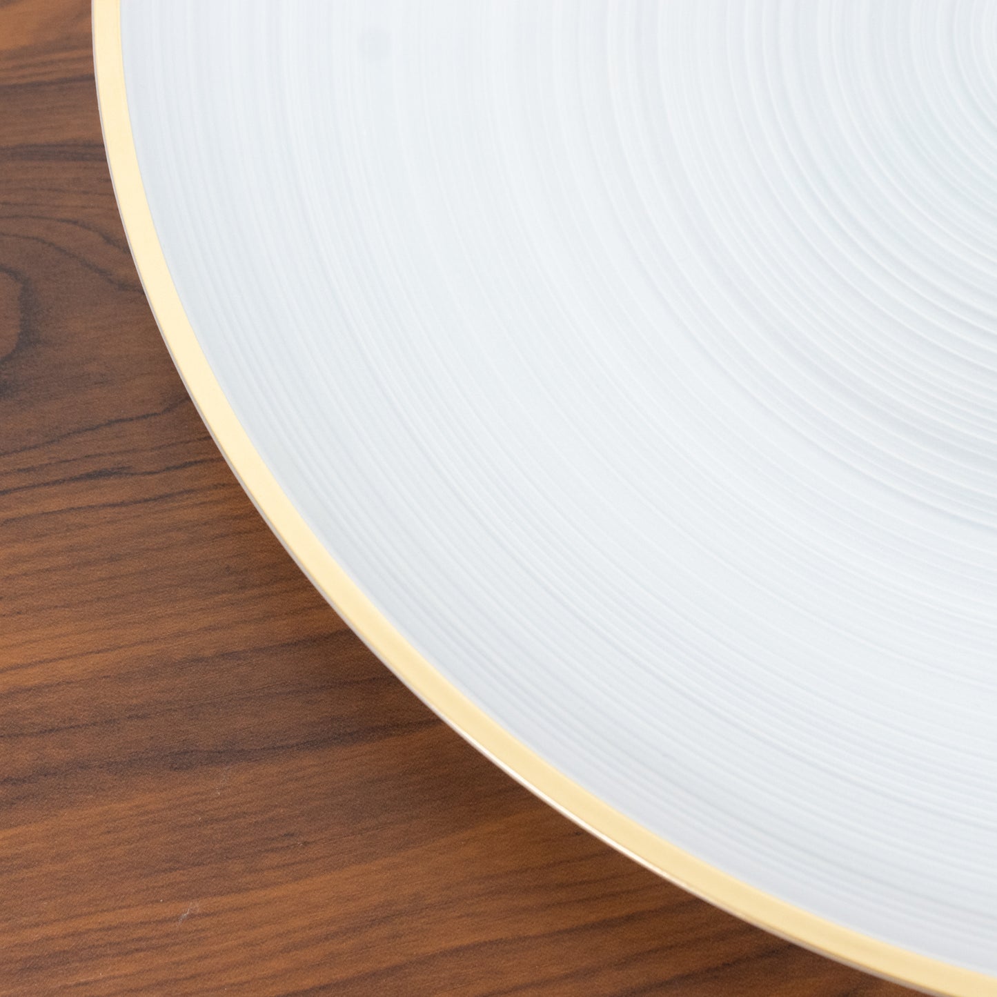 Transparent pearl white swirl charger plate with gold rim.