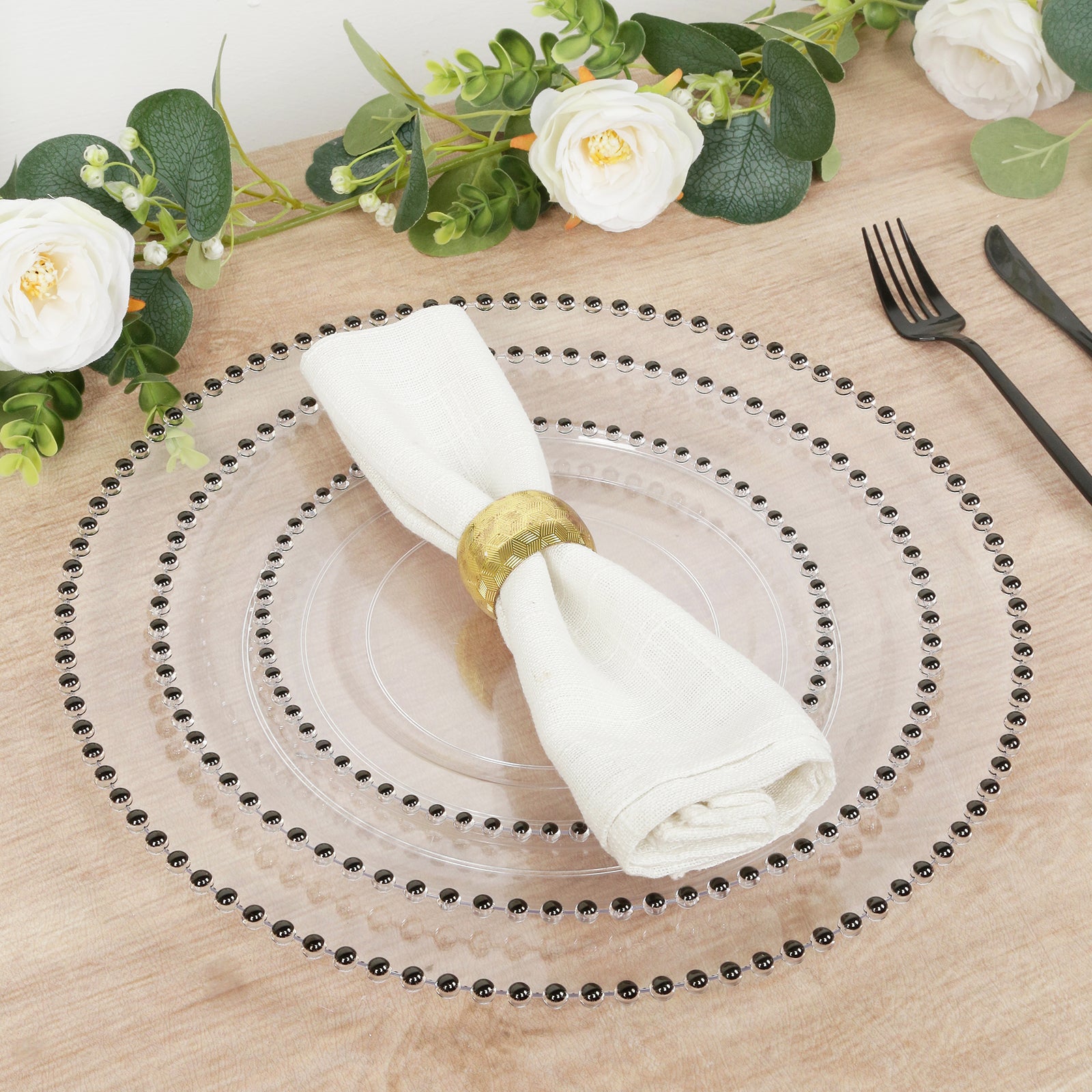 Clear plastic charger plate with black beaded rim, stylish dinner party setting.