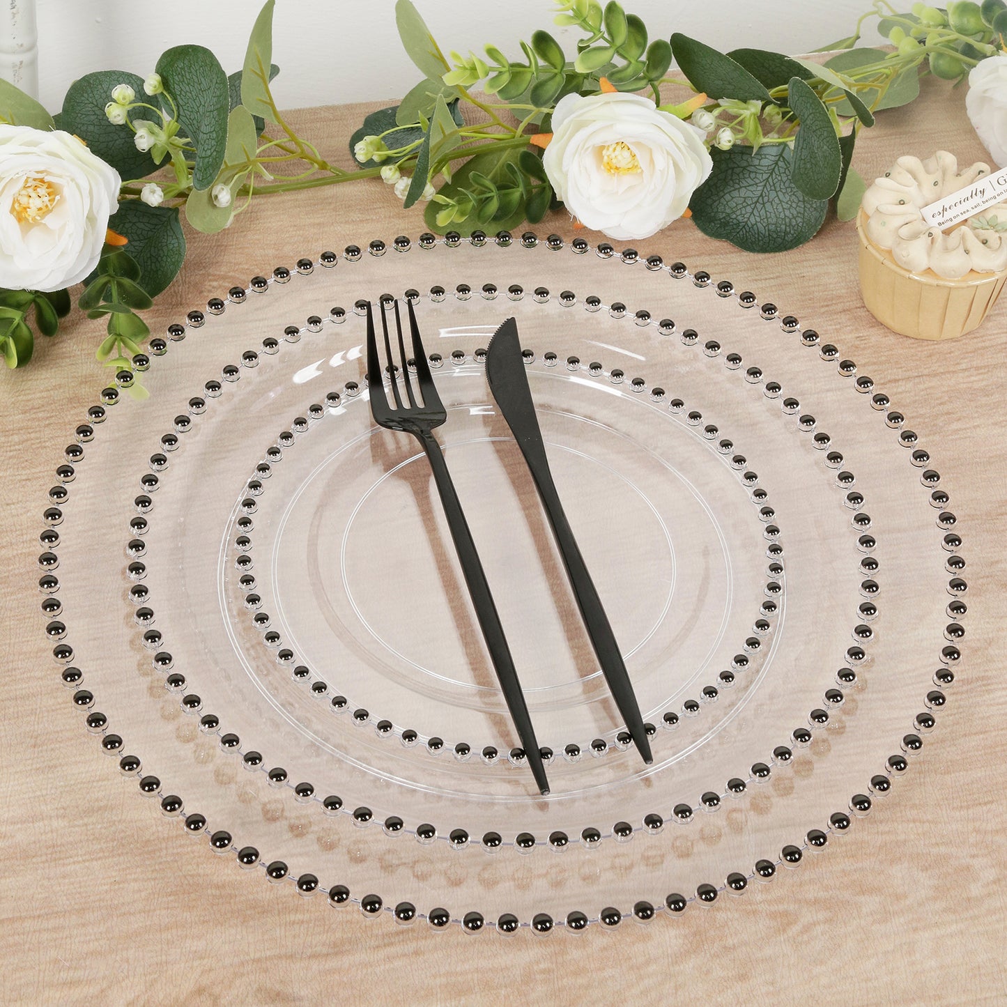 Clear charger plates with black beaded rim for stylish dinner parties.