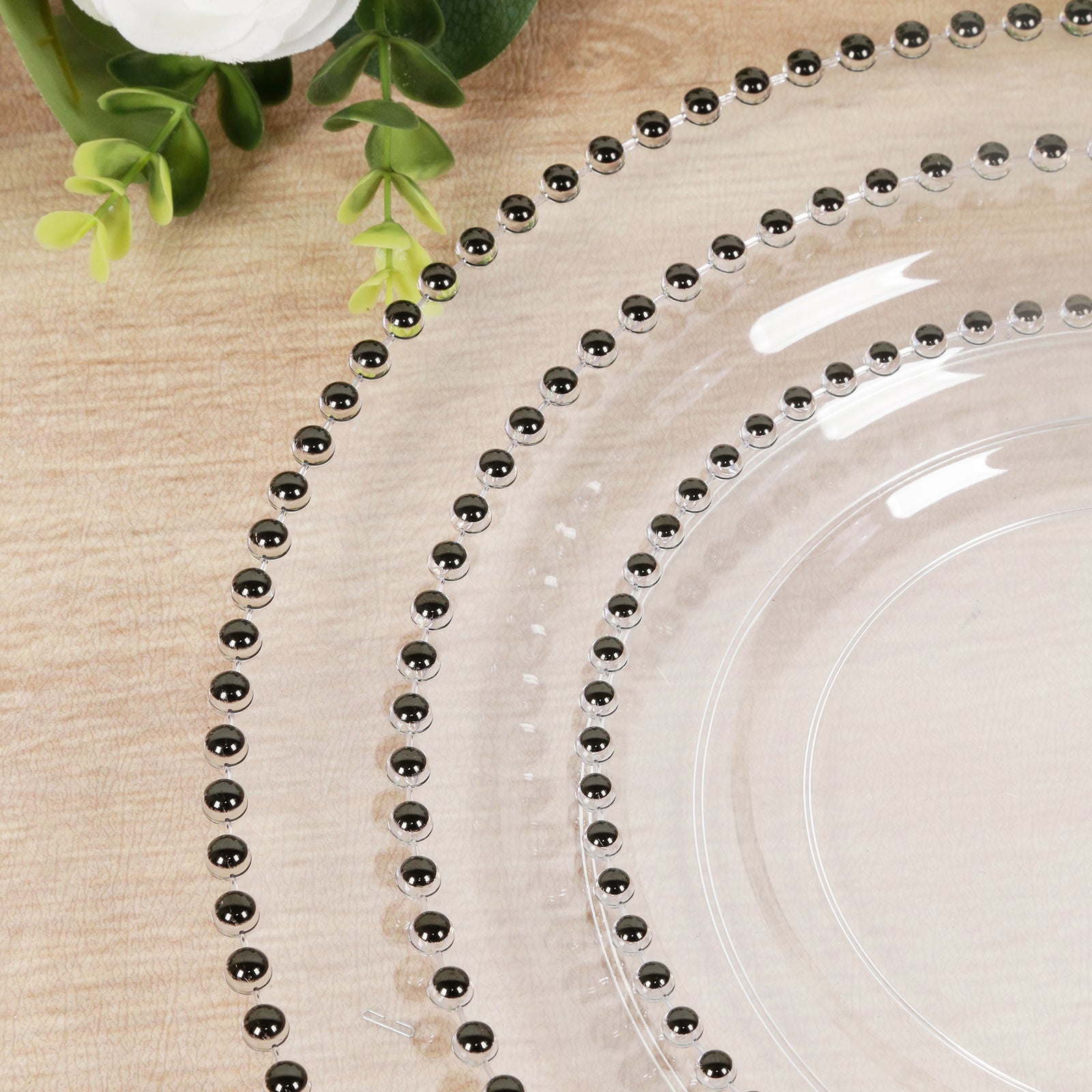 Clear plastic charger plate with black beaded rim, perfect for stylish dining.
