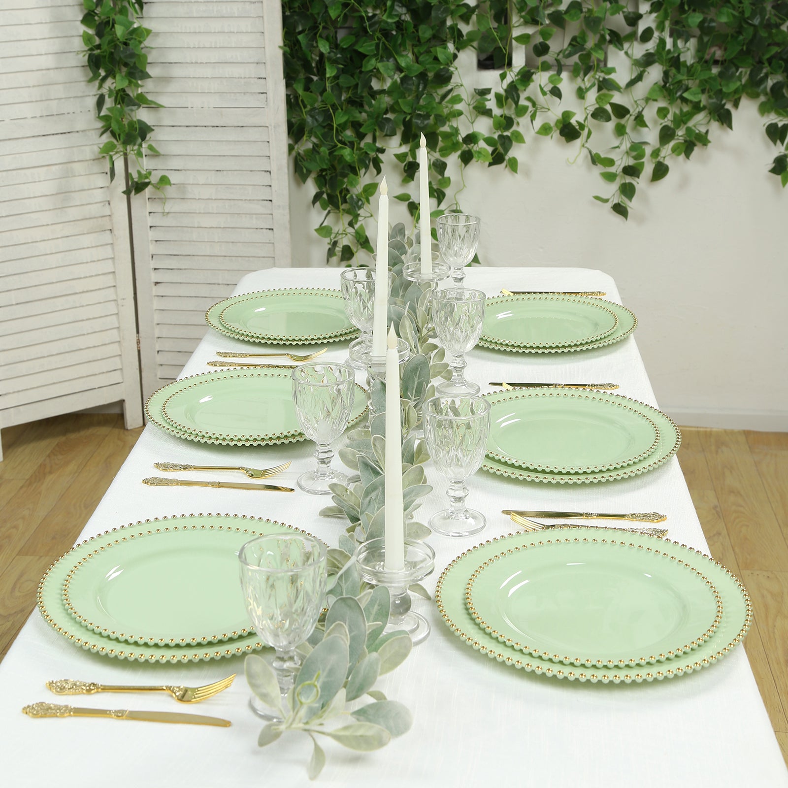 Sage green charger plates with gold beaded rim on a dining table setting.