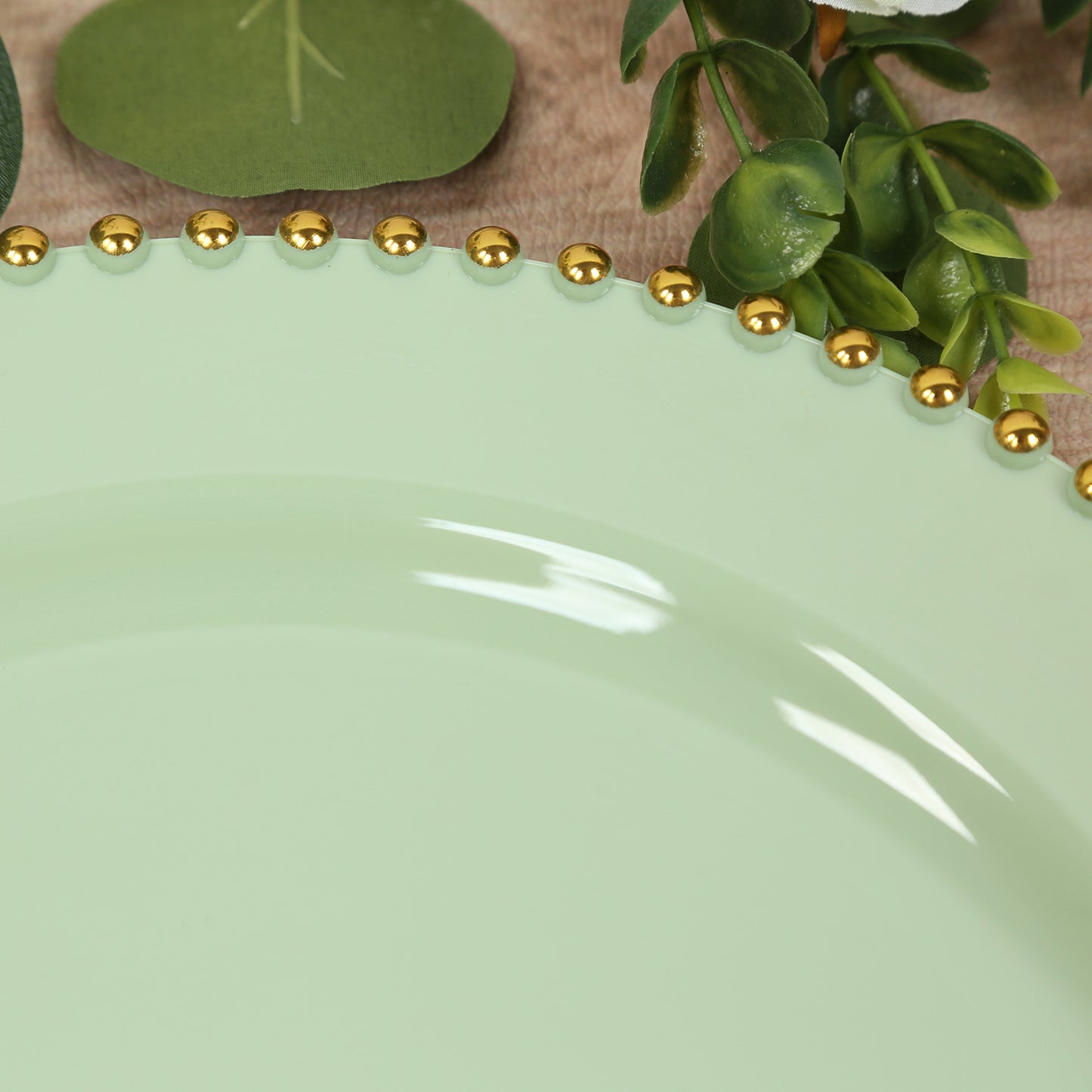 Sage green charger plate with gold beaded rim.