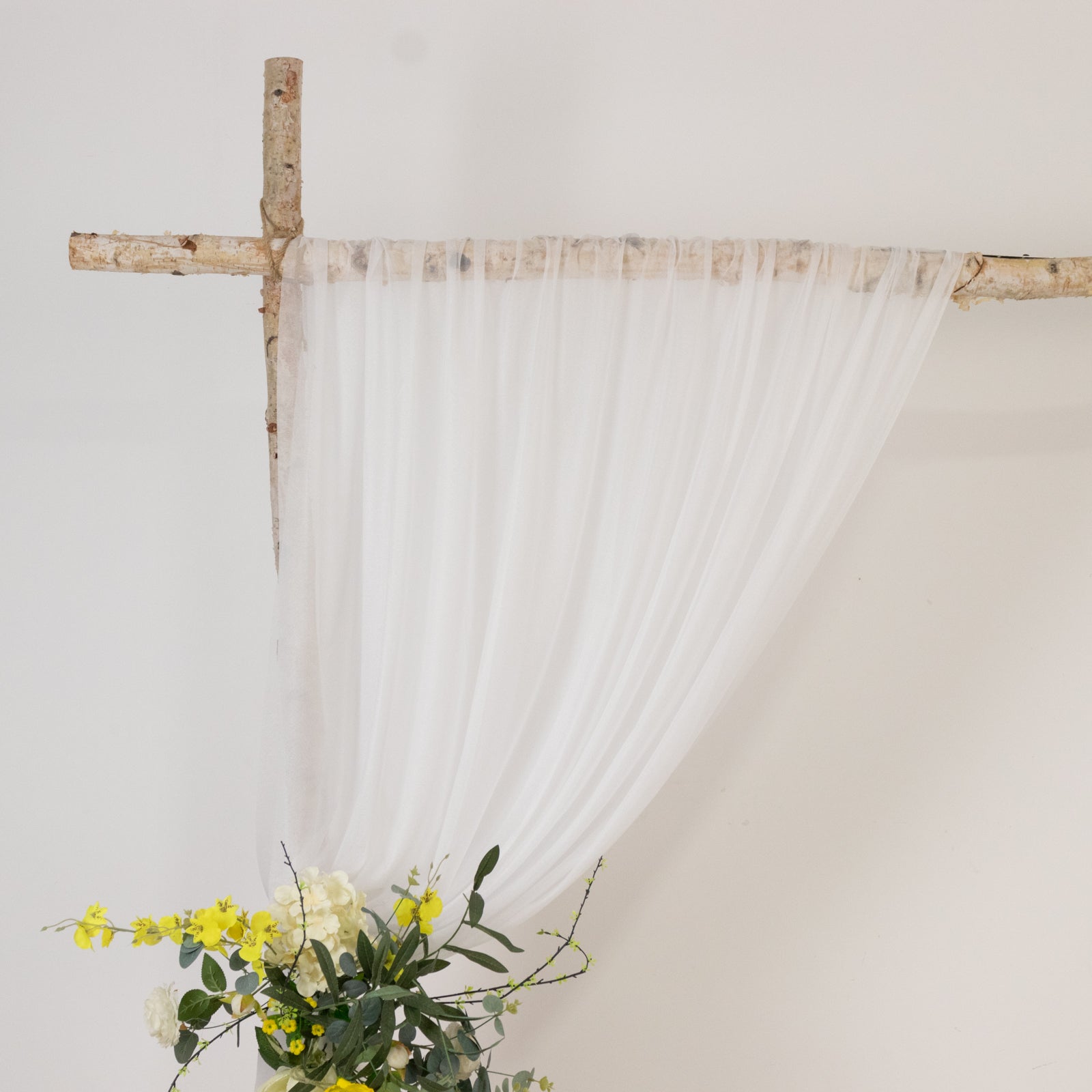 Blush sheer curtain draped elegantly over natural wood decor with floral arrangement.