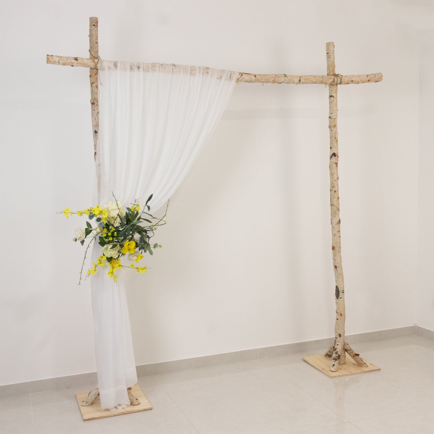 Blush wedding arch with sheer drapery and floral arrangement. Perfect for ceremonies.