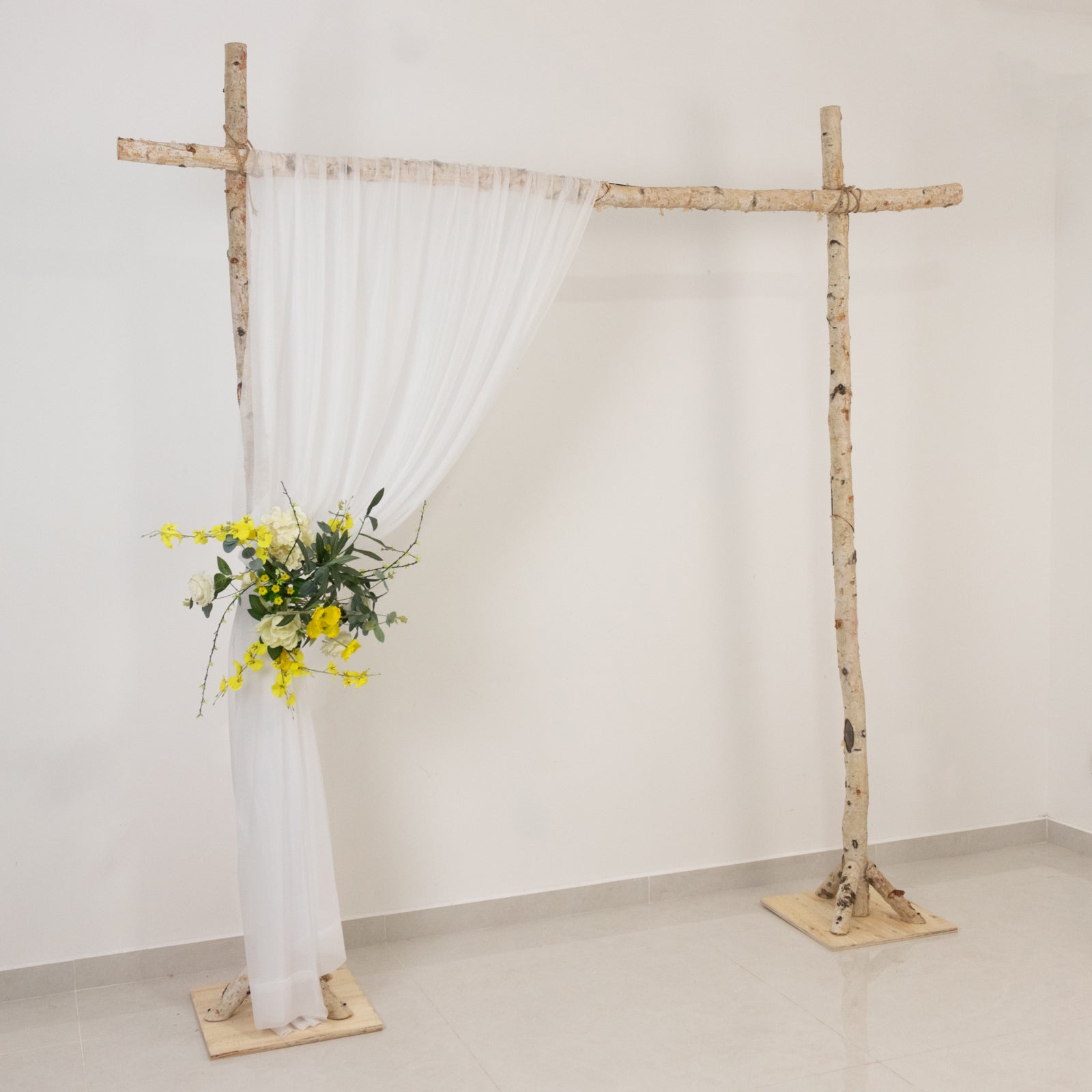 Blush wedding arch with sheer drapery and floral arrangement. Perfect for ceremonies.