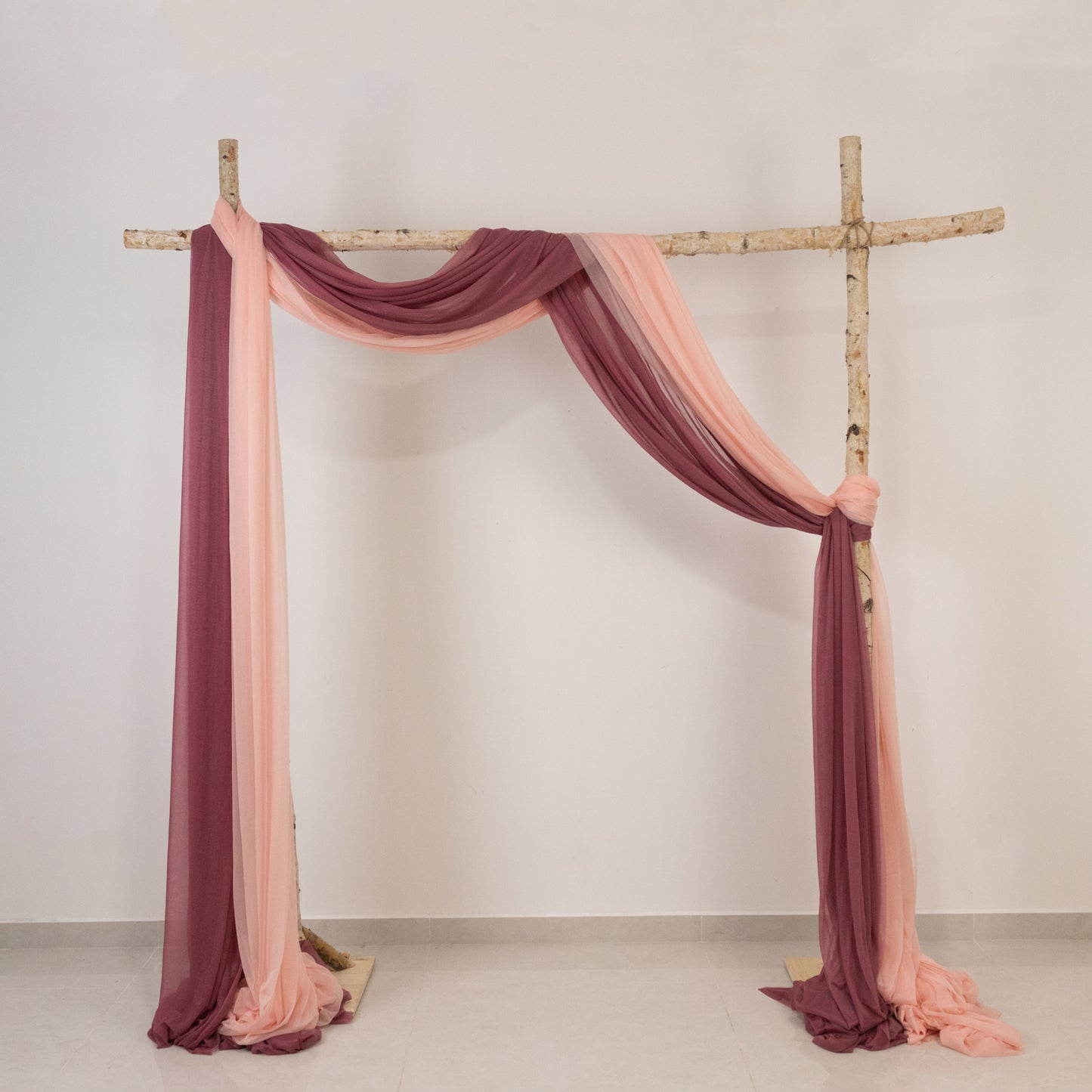 Blush sheer backdrop drape on a wedding arch with soft shimmer details.