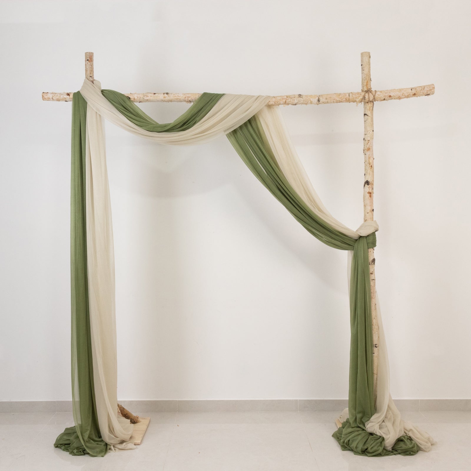 Beige sheer backdrop drape on a wedding arch with green accents.