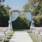 Dusty blue sheer curtain panel draping a wedding arch with floral accents.