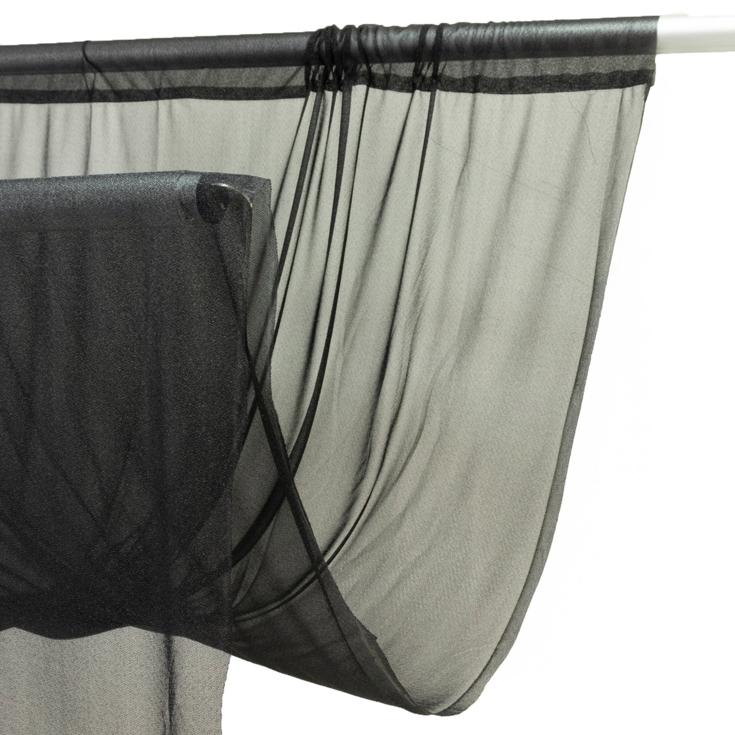 Black sheer backdrop curtain panel hanging on a rod.