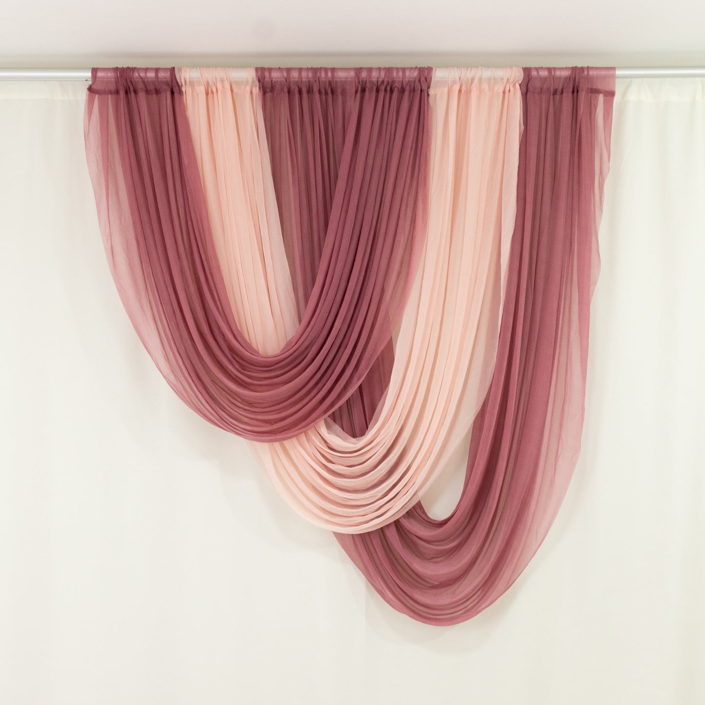 Blush chiffon backdrop valance drapes with a curved swag design.