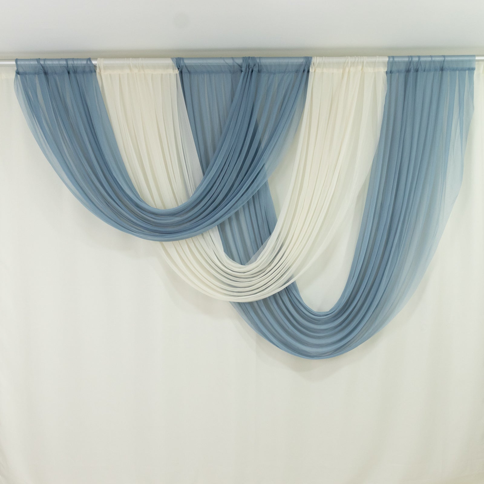 Ivory and blue sheer chiffon backdrop valance drapes in a curved swag design.