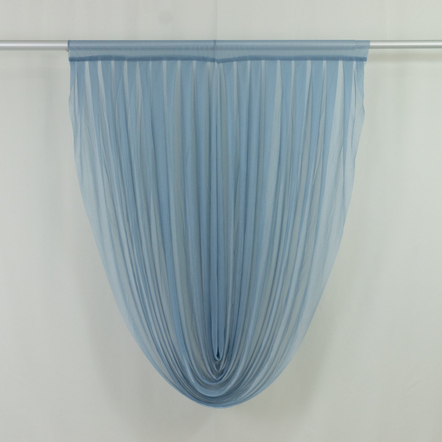 Dusty blue sheer chiffon valance curtain draped on a rod.