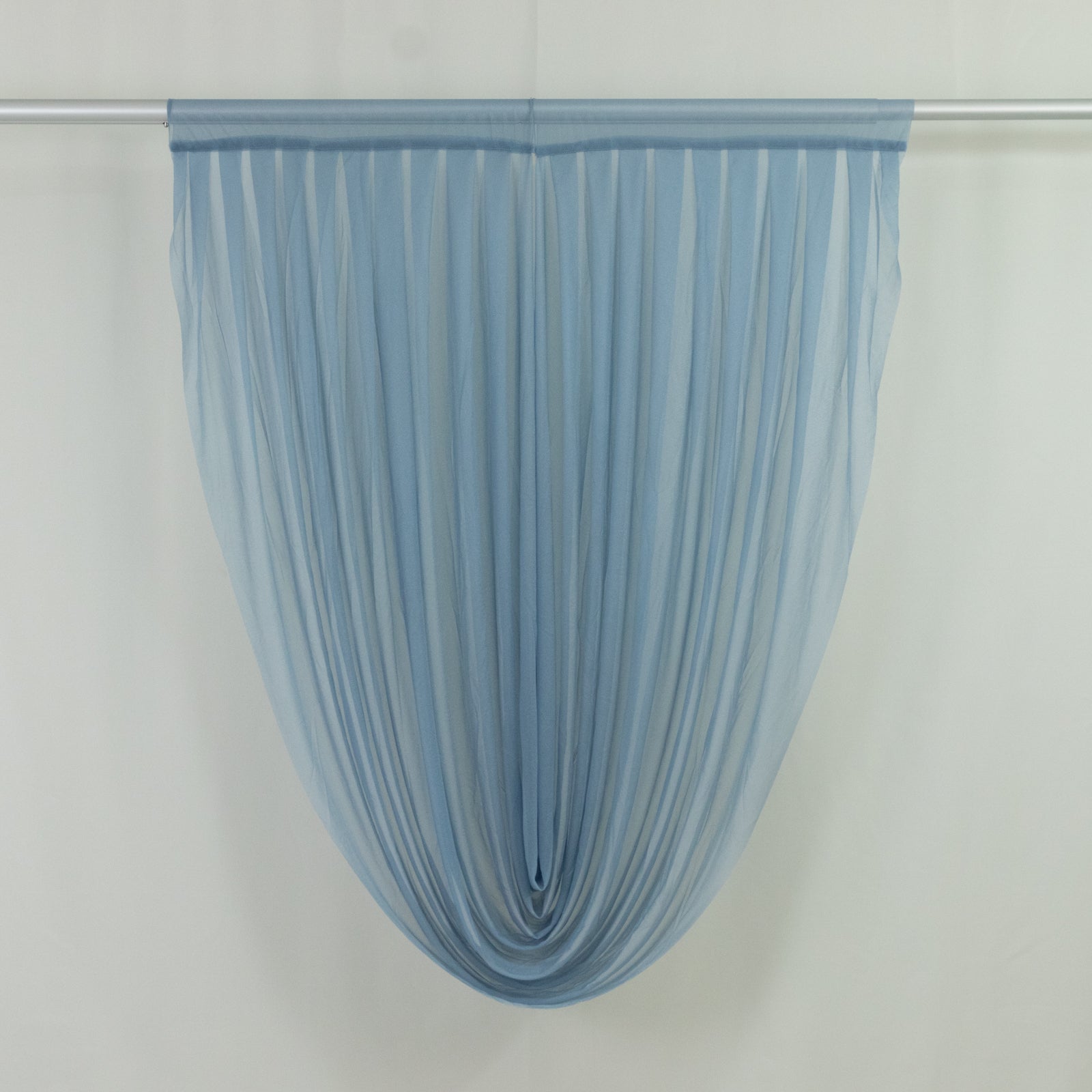 Dusty blue sheer chiffon valance curtain draped on a rod.