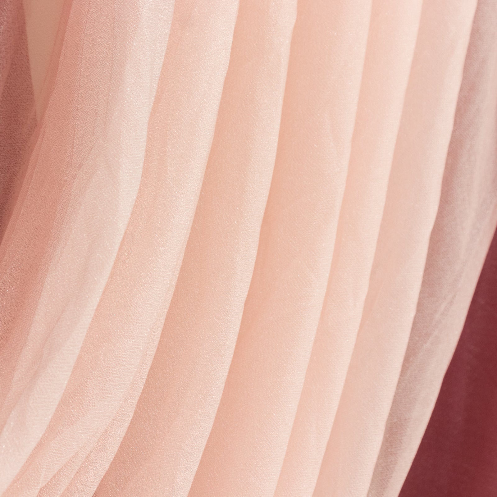 Blush tulle fabric draping elegantly in soft layers.