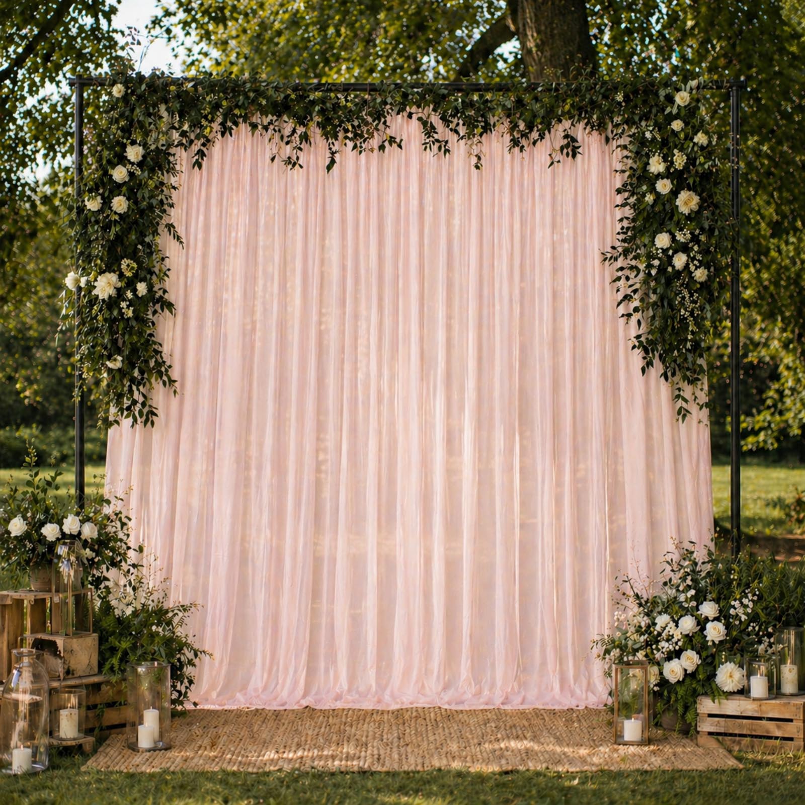 Blush chiffon backdrop curtain panel with floral decor and greenery.