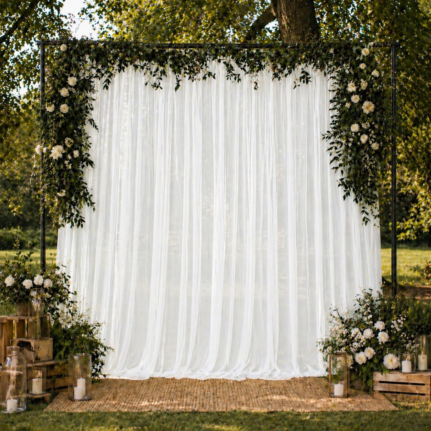 White chiffon backdrop curtain panel with floral decor and greenery.
