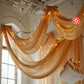 Gold chiffon curtain panel draping elegantly with lights in a bright setting.
