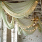Sage green chiffon curtain panel draping with fairy lights.