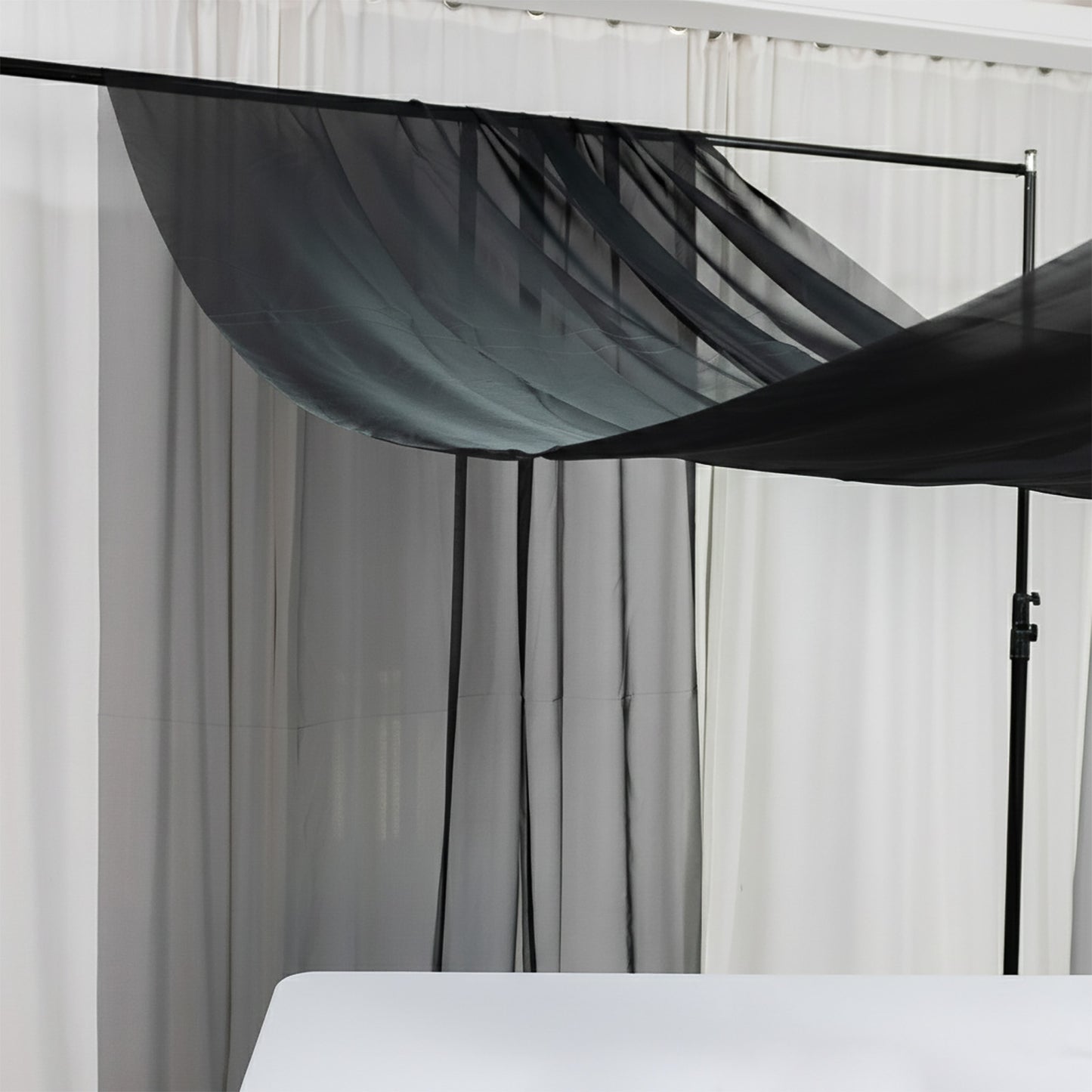 Black chiffon curtain panel draping elegantly in a bright room.