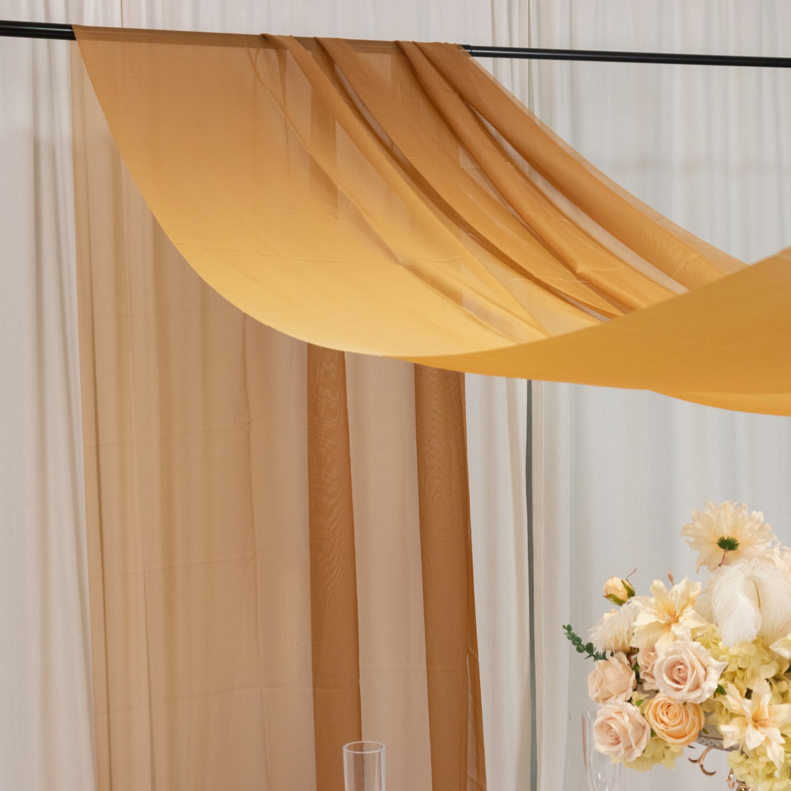 Gold chiffon curtain panel draping elegantly over a rod.