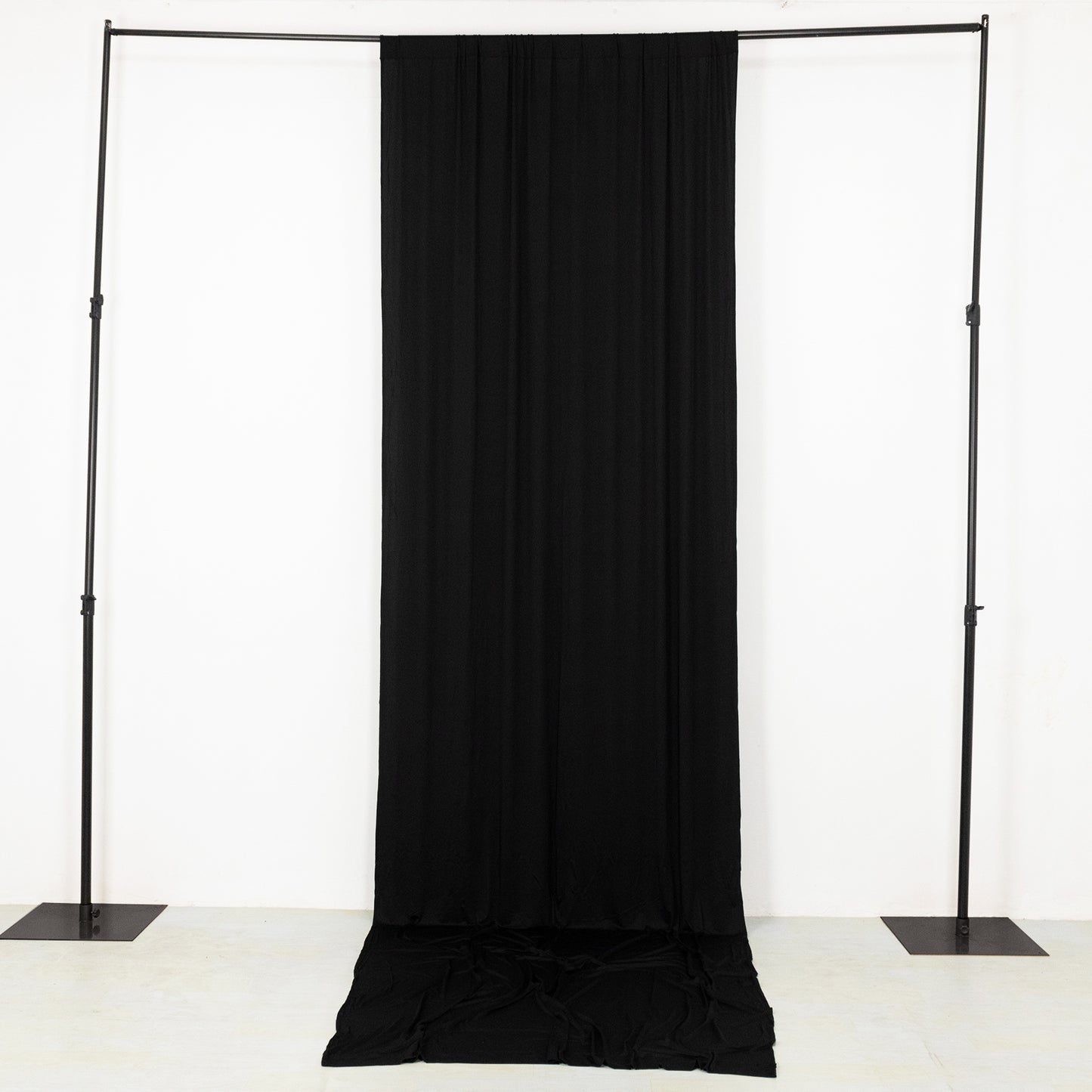 Black 4-way stretch spandex event curtain drapes on a backdrop frame.