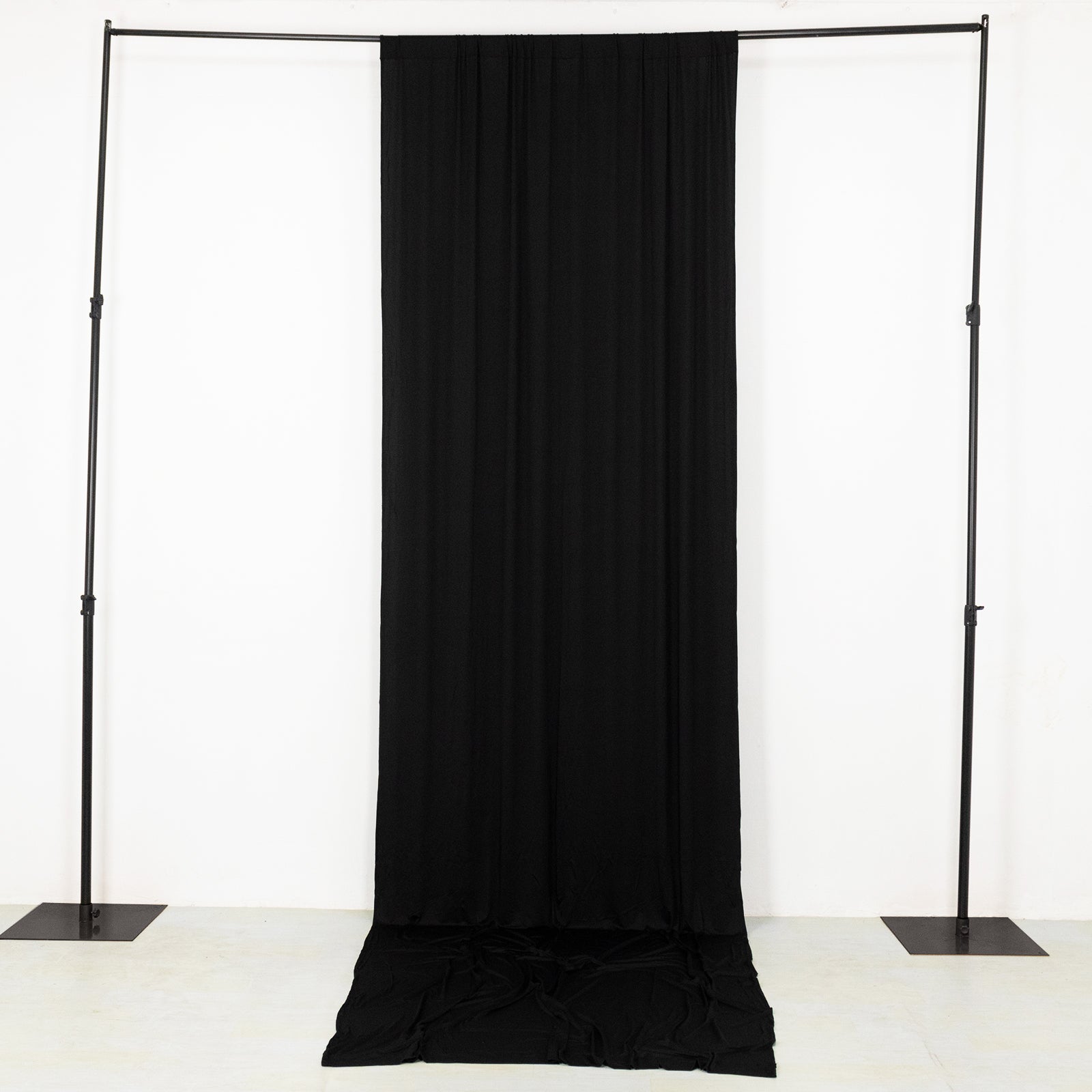 Black 4-way stretch spandex event curtain drapes on a backdrop frame.