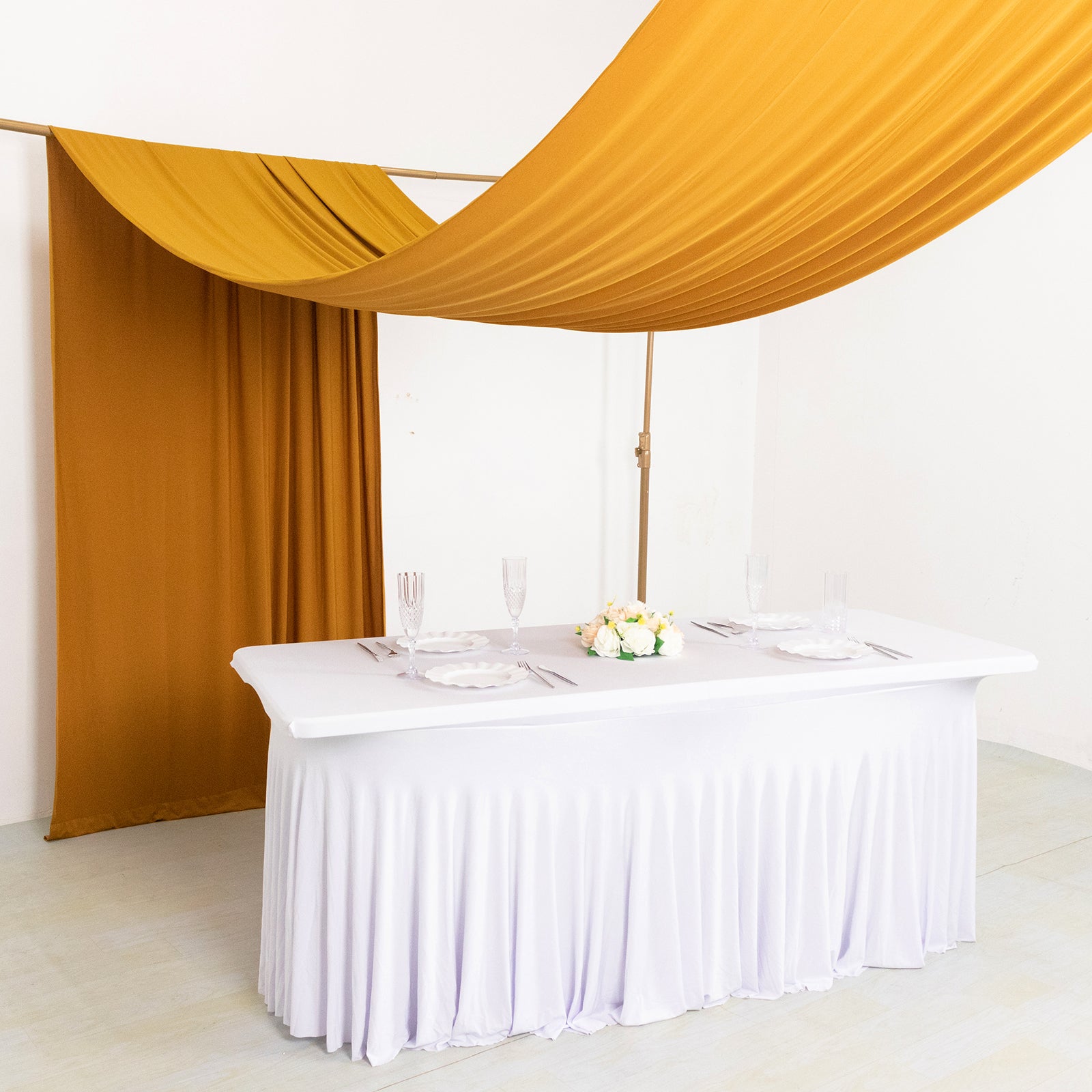 Gold 4-way stretch spandex backdrop drapes elegantly above a white table.