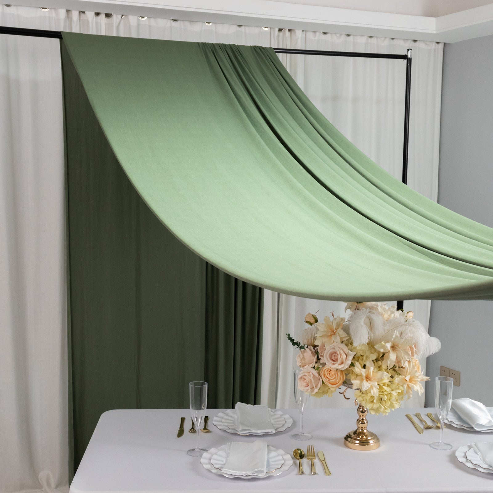 Dusty sage green 4-way stretch spandex event curtain drapes on a backdrop.