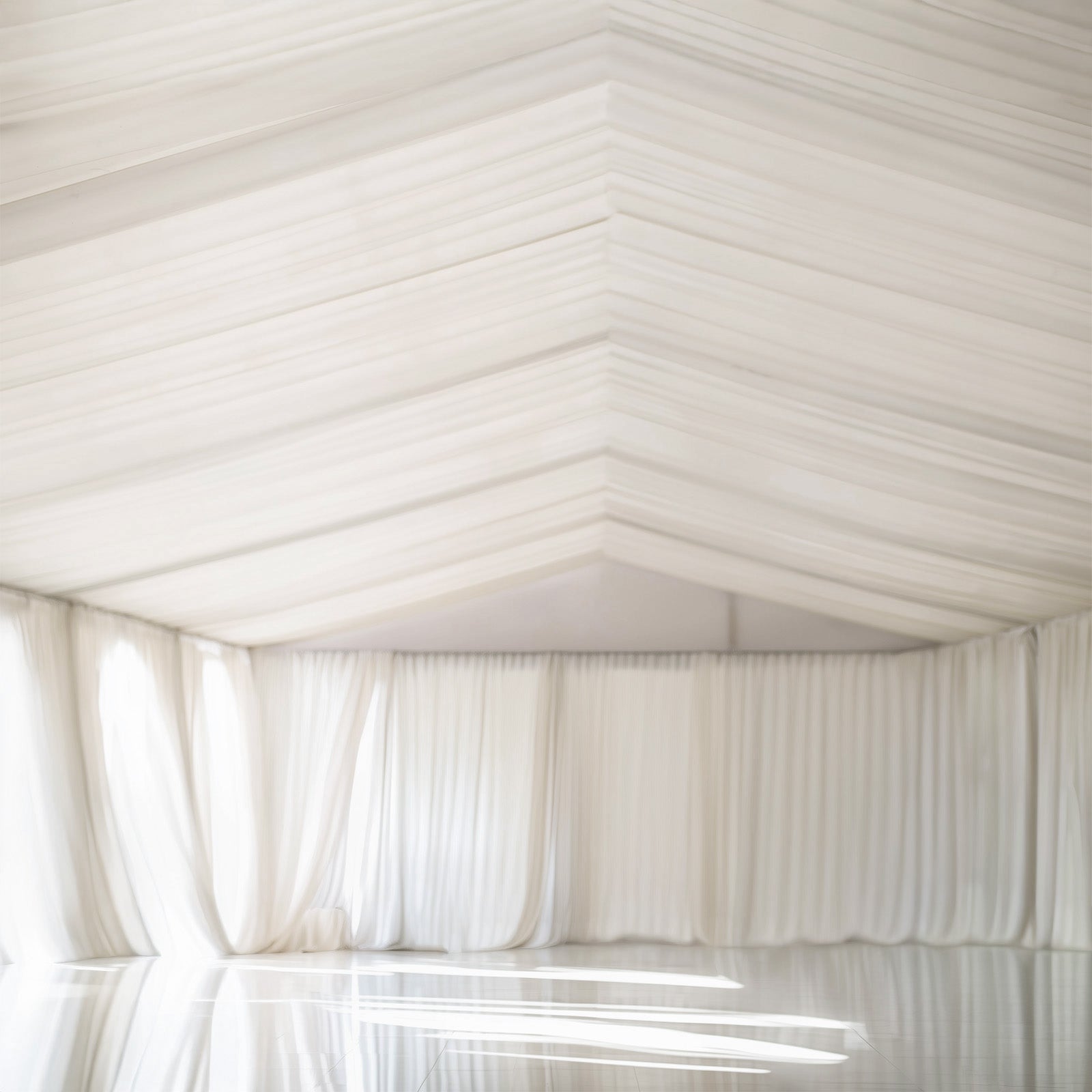 Ivory stretch spandex tent ceiling drape in a spacious setting.